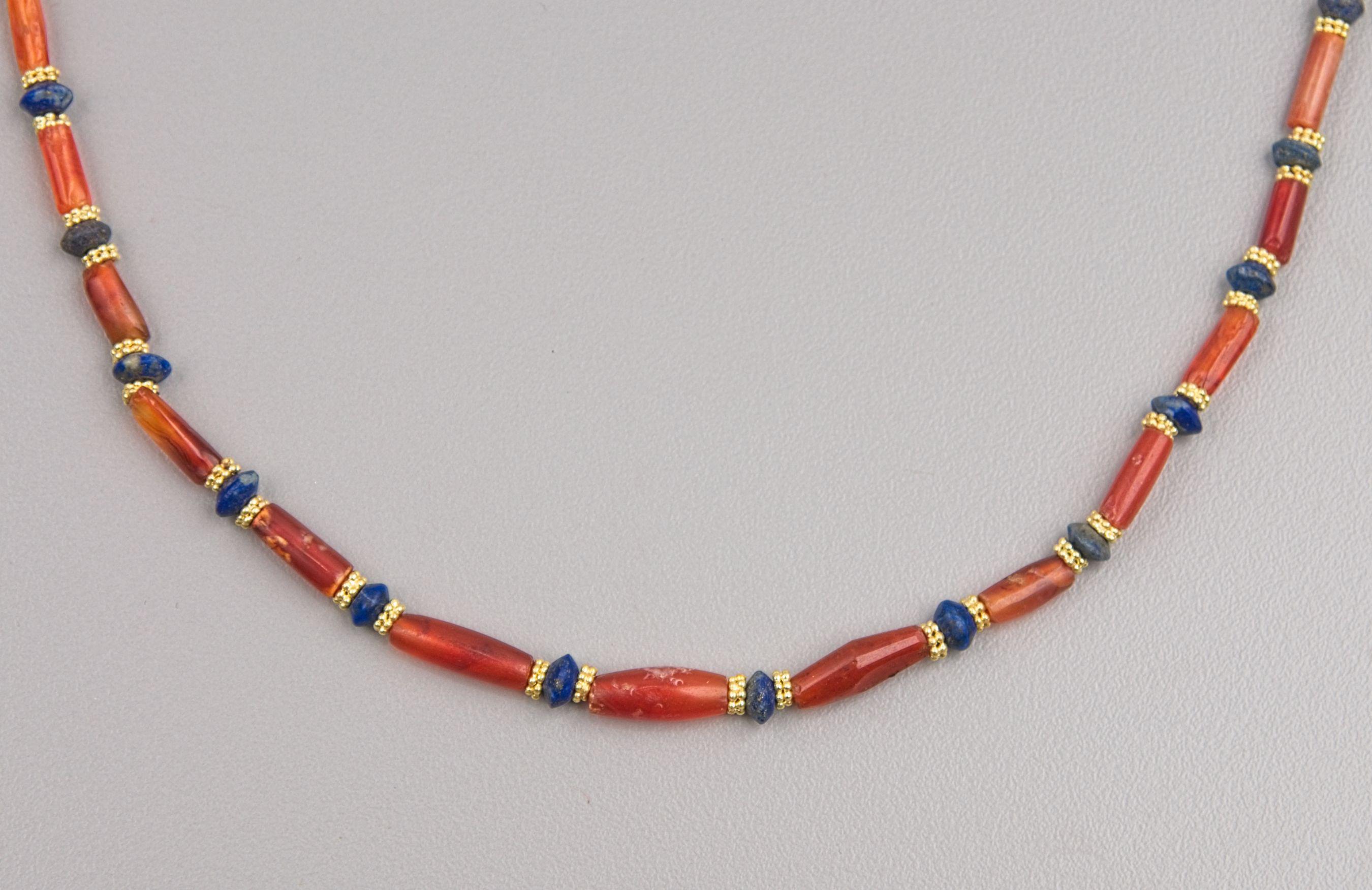 Thirty-three cylindrical, bi-conical and tapered barrel shaped carnelian beads alternating with thirty-four bi-conical disc shaped lapis lazuli beads. Each of the lapis lazuli beads are faced with a granulated 22k ring bead of two tiers circlets of