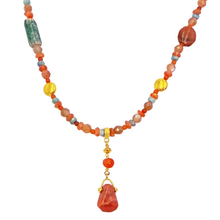 The 22k yellow gold pendant features two ancient artifact Carnelian beads, and hangs from a multi-gemstone beaded necklace. Beaded necklace includes Sunstone, Carnelian, Chrysocolla, Picasso Jasper, Colosseum Stone, and 22k gold discs, as well as