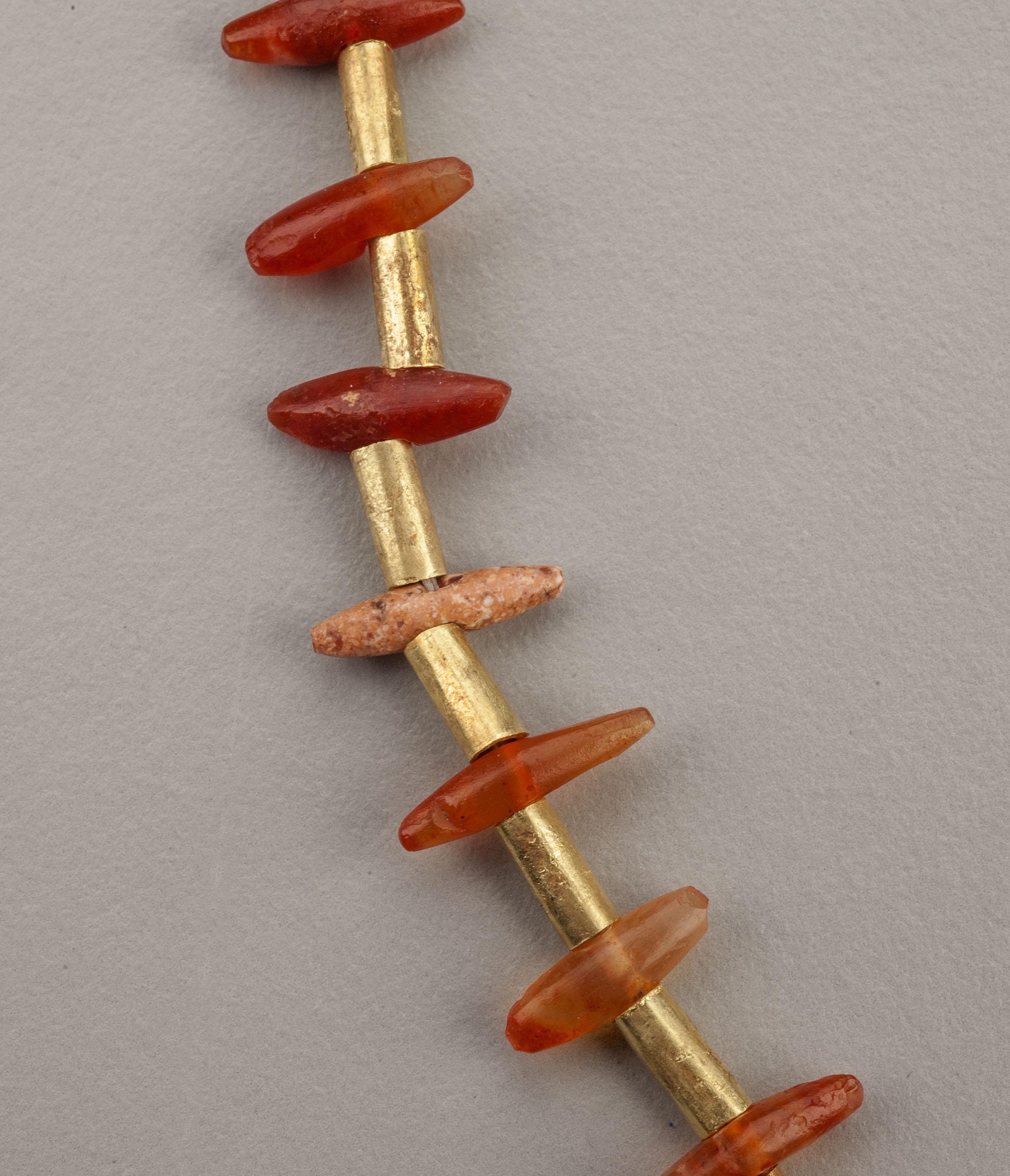 A necklace of fifty-five carnelian beads alternating with fifty-four 22k gold tube beads. Fifty-three of the carnelian beads are of an unusual form being long spar shapes pointed on each end and drilled through the middle. The width at the middle