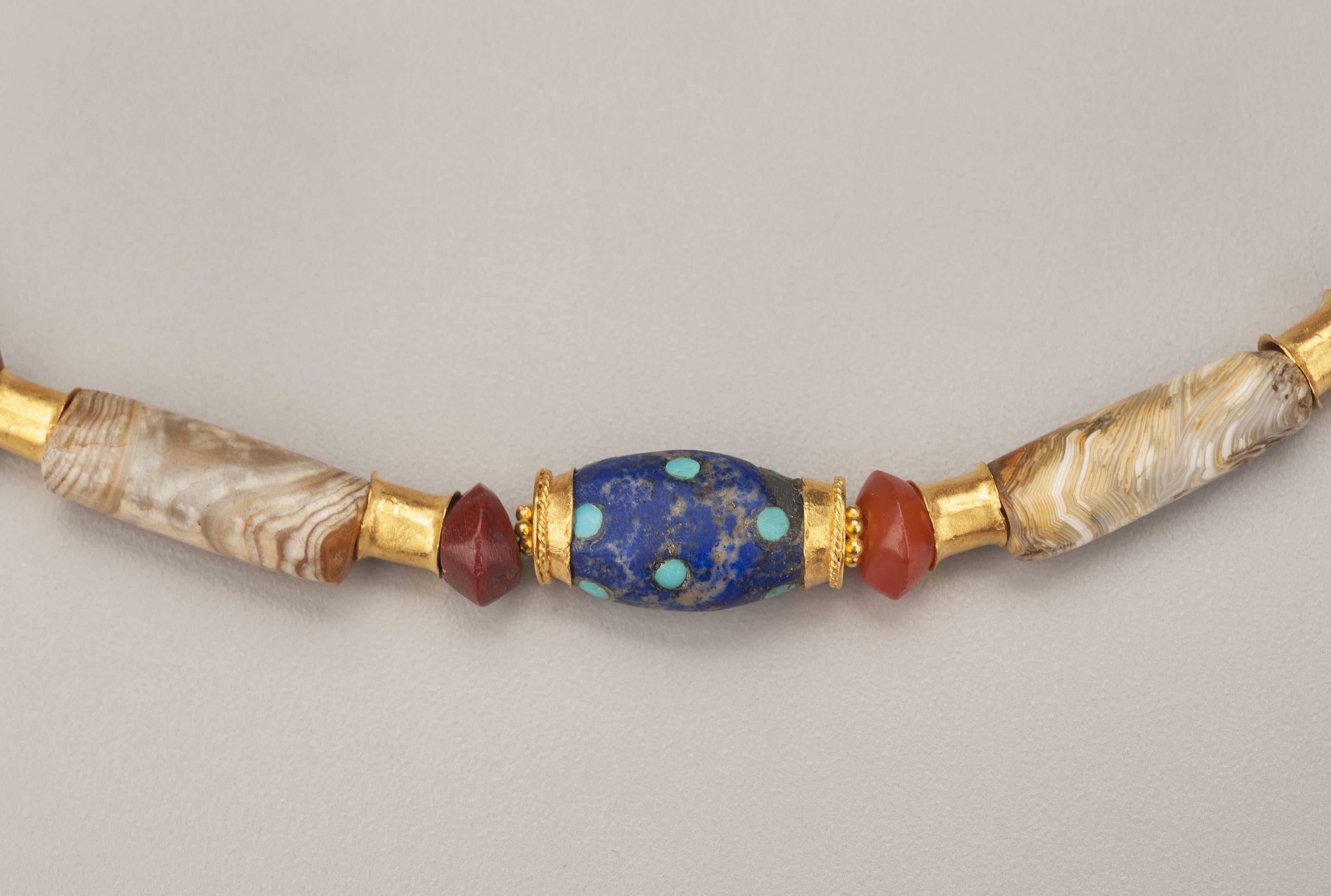 Eight ancient agate barrel beads faced with sixteen flared 20k gold tubes and alternating with eight lapis lazuli short bicone beads faced with pairs of two layer gold granulated ring beads; eighteen carnelian bicones and short barrel beads separate