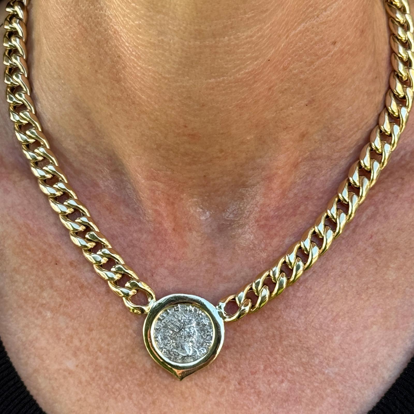 Ancient coin necklace crafted in 14 karat yellow gold. The necklace features an ancient coin set in a gold frame measuring 1.00 in diameter. The cuban link necklace measures 16 inches in length wit box clasp. 
Weight: 45.6 grams.