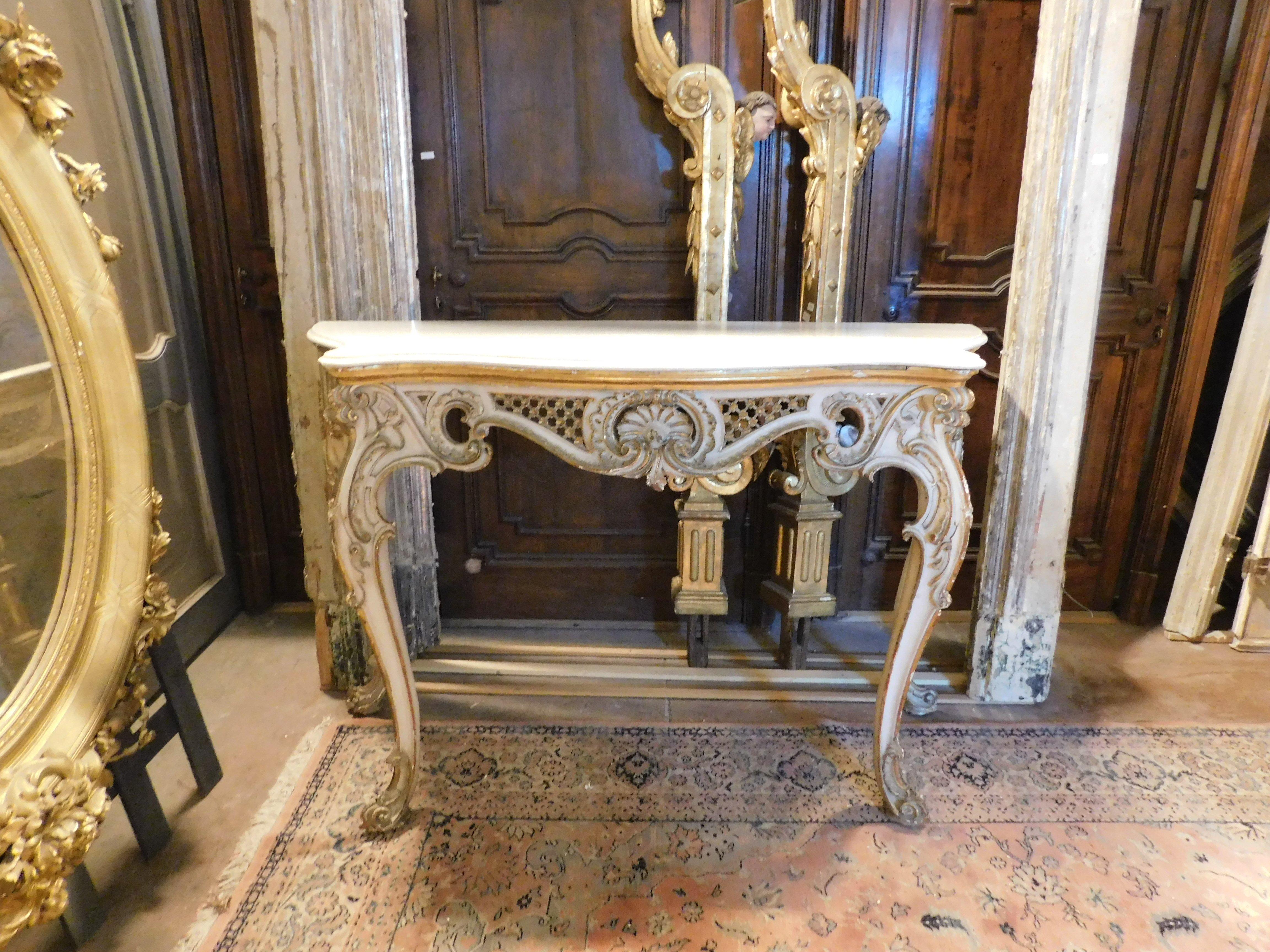 Antique console in poplar wood, lacquered and gilded by hand, richly carved with floral decorations on the legs and front with central shell. complete with original white marble top. Perfect for multiple furnishing solutions, a beautiful presence