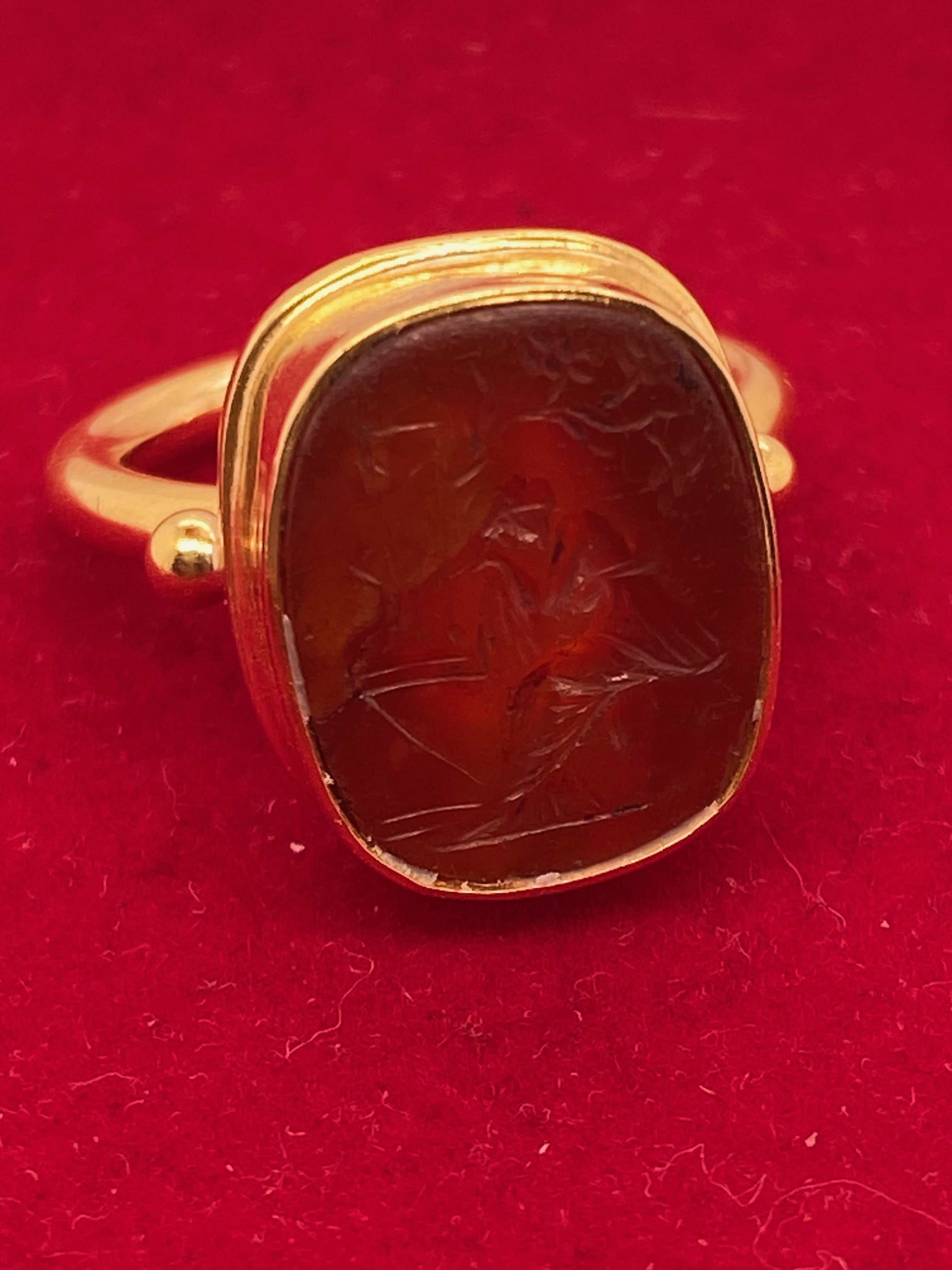 Cushion Tablet Form graviert Ancient Carnelian Intaglio in einem zeitgenössischen Etruscan Revival Ring gesetzt.
Der Ring ist hochglanzpoliert reich 22kt Gelbgold. Das antike Intaglio ist in eine Lünette gefasst. Zwei 2,7-mm-Goldperlen sitzen