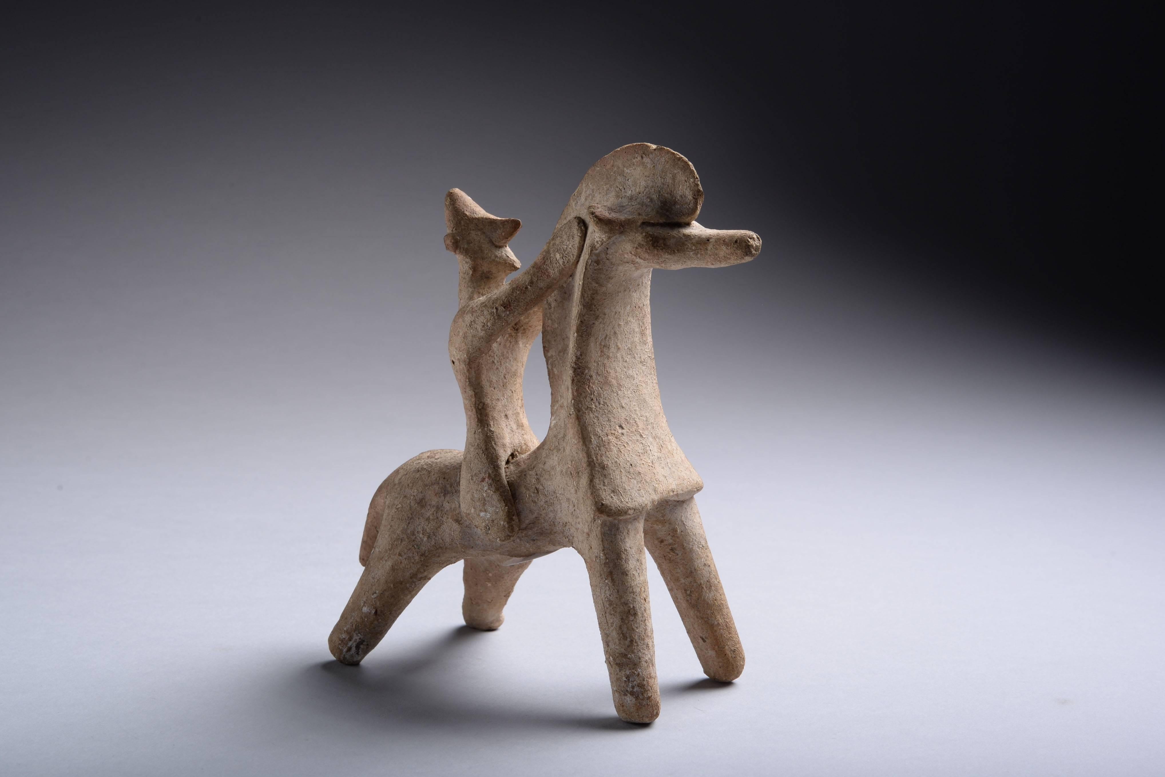 A terracotta model of a warrior on horseback, from Cyprus, dating to the Cypro-Archaic period, circa 7th - 6th century BC. 

The horse standing with head raised, the helmeted rider holding onto its mane with both hands. 

A wonderful example of
