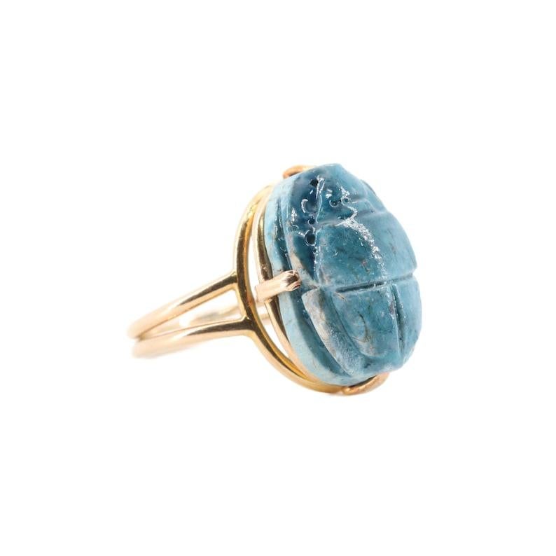 Aston Estate Jewelry Presents:

A circa 1920's handmade 14 karat gold ring centered by a genuine ancient Egyptian scarab. Dating back over 2000 years in age, the beautiful glazed clay scarab is of a pleasing turquoise blue color. Mounted in the