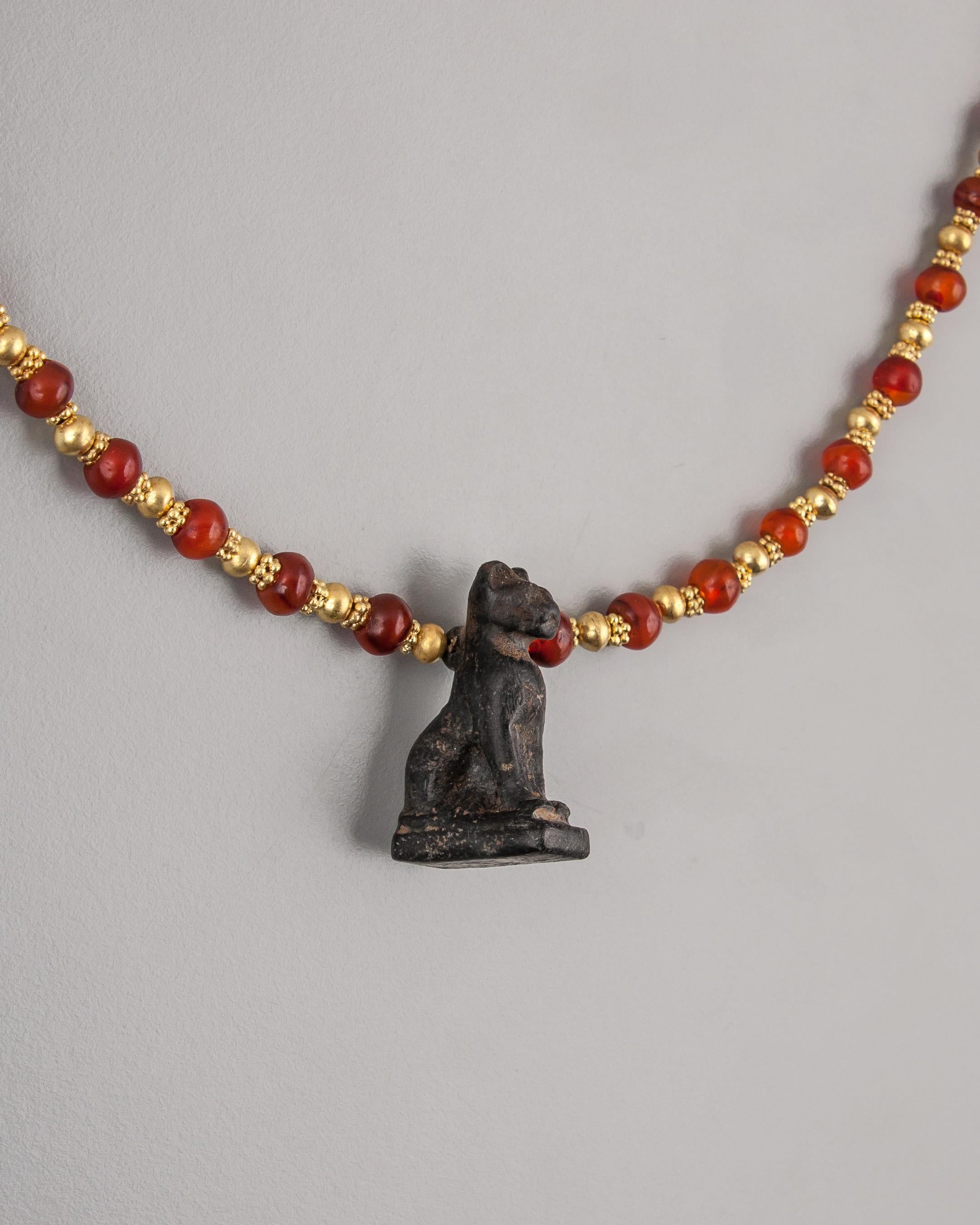 Forty-six ancient Egyptian carnelian beads with one hundred thirty-eight 20k gold beads and a black stone depiction of Bastet, the cat goddess of Bubastis. A 20k gold clasp and beading tips completes the necklace. The cat pendant is 3.5 cm tall, the