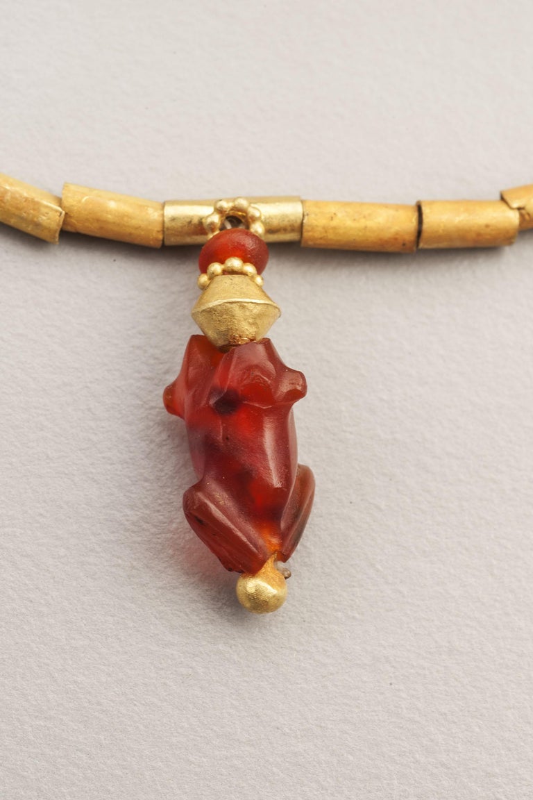 Sixty-two 22k gold tube beads with six cylindrical carnelian beads and a carnelian frog bead suspended from the apex of the necklace. The frog is 1.8 cm in length and 7.2 mm in width at the knees where the legs are folded back upon themselves. The