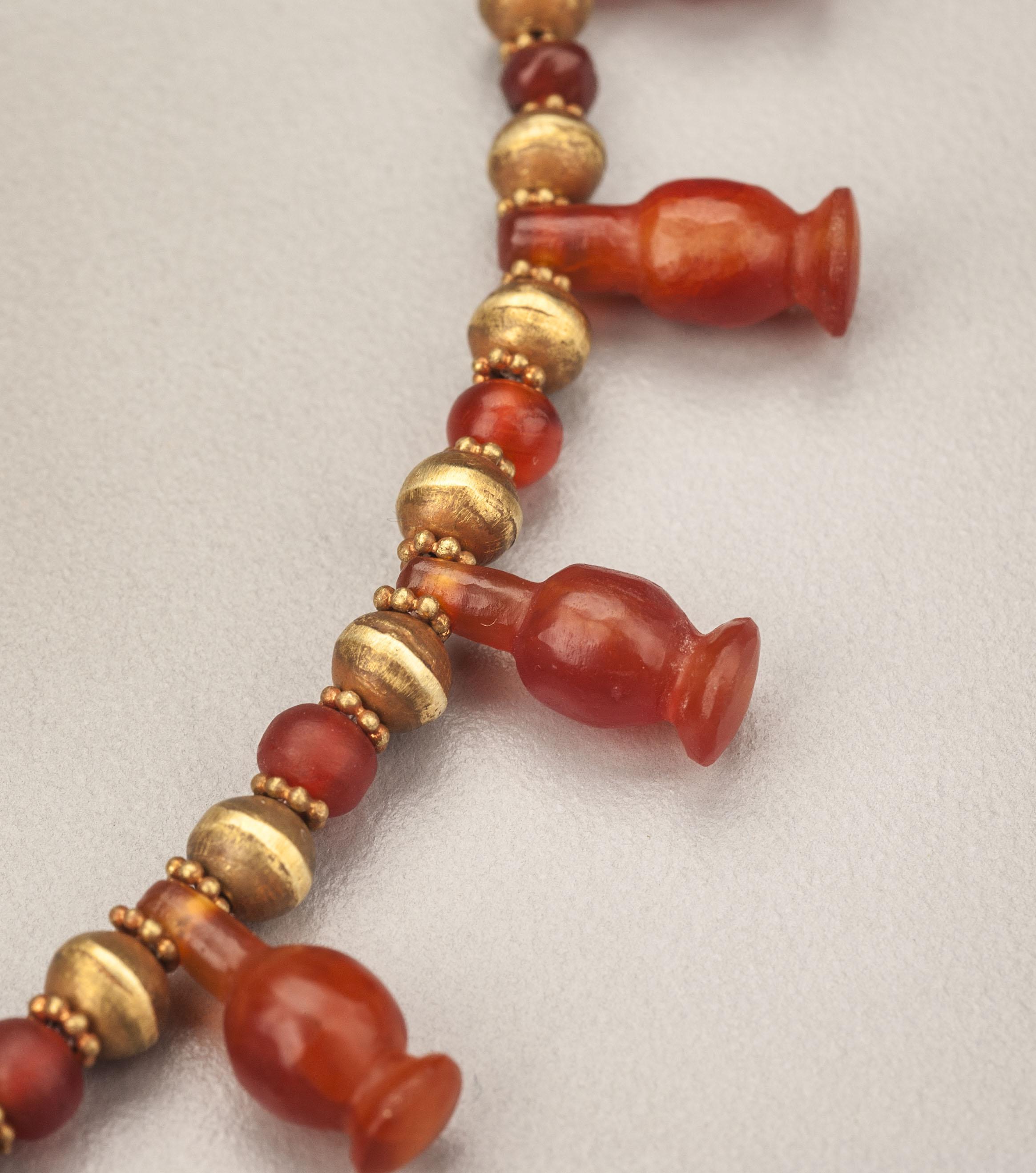 Thirty ancient Egyptian carnelian poppy seed pods pendant beads, faced with gold granulated ring beads, and alternating with round carnelian beads also faced with gold granulated ring beads; with gold round beads alternating between the carnelian