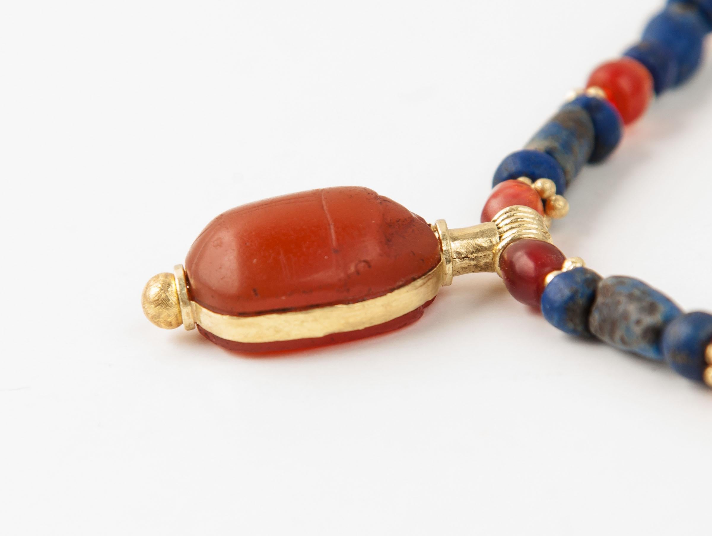Ninety lapis lazuli beads, thirty-two carnelian beads and sixty granulated gold ring beads with a carnelian scarab pendant on a gold mount. The lapis lazuli beads are strung in groups of three with the center barrel bead flanked on either side with