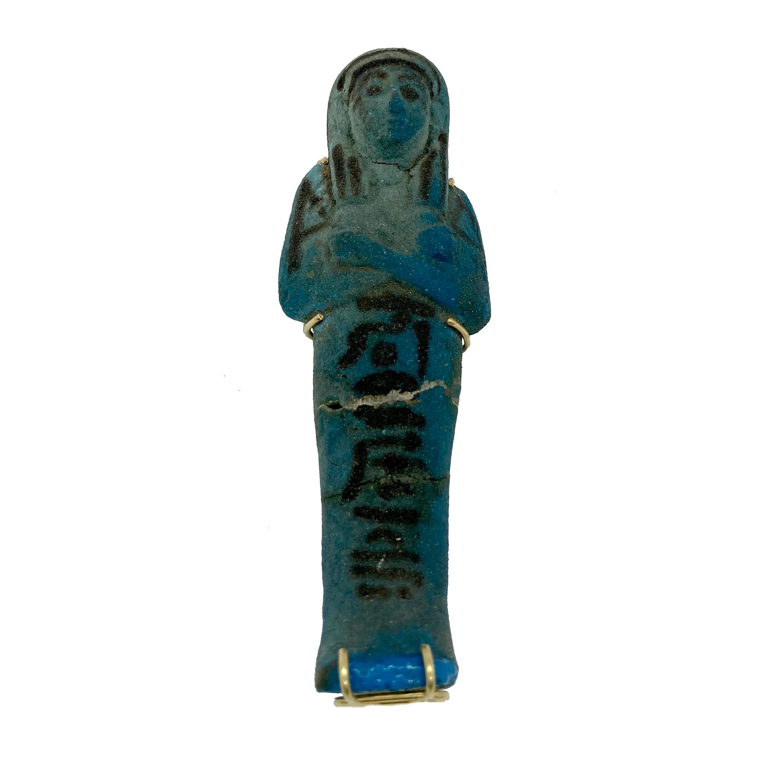 Eine altägyptische Grabfigur aus Fayence in einer modernen goldenen Anhängerfassung.