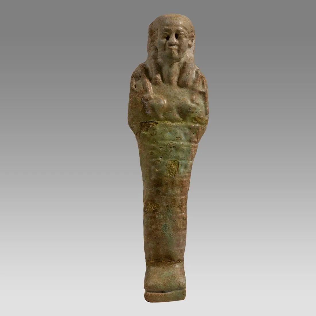 Un'impressionante figura di Faience Ushabti dell'Antico Egitto, appartenente al periodo compreso tra il 700 e il 30 a.C. Si tratta di una ceramica modellata con una superficie smaltata di verde. La figura indossa una parrucca regale e una barba