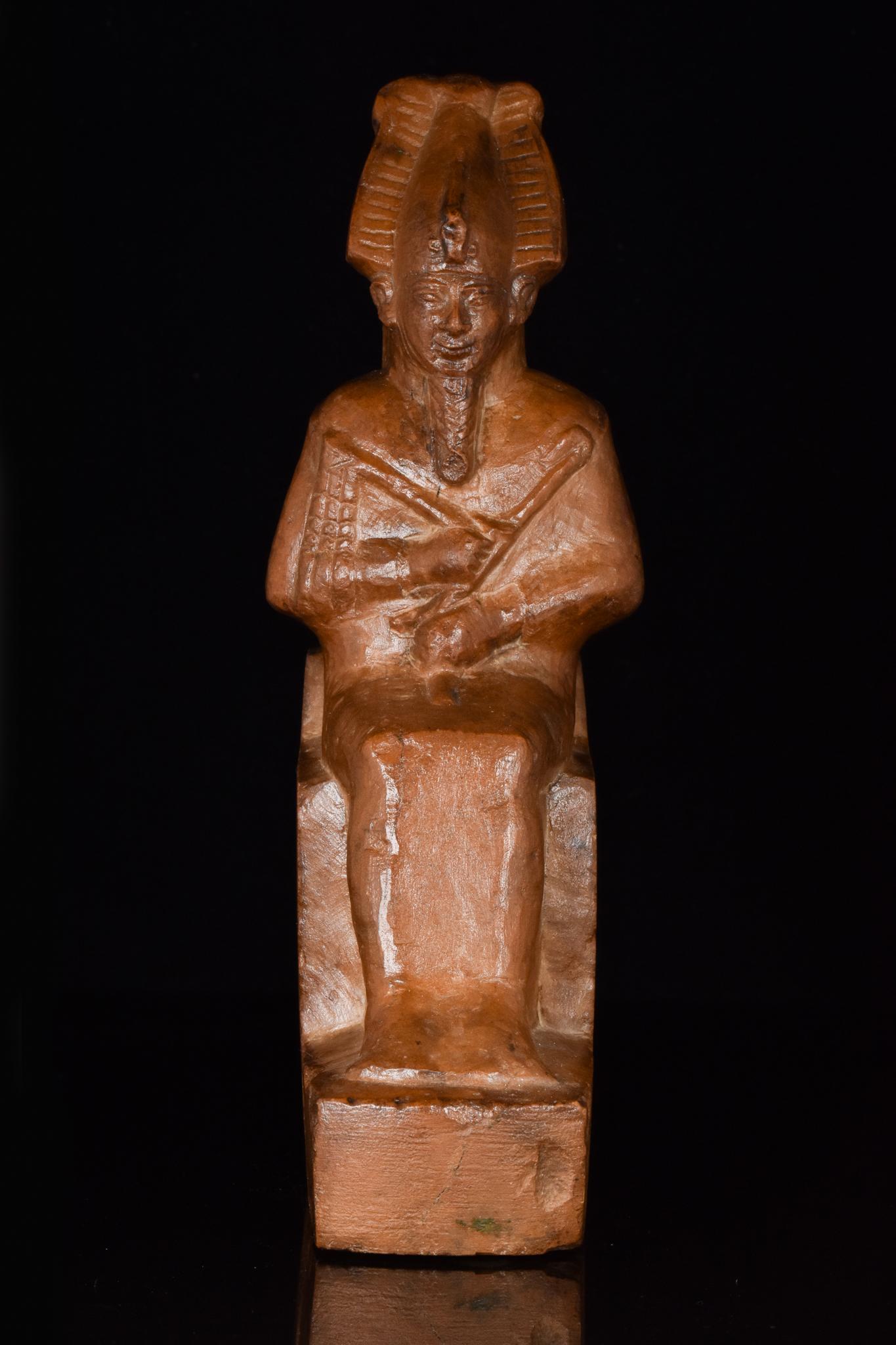 Circa 664-332 BC, Late Dynastic Period

An ancient Egyptian stone statuette depicting the god Osiris. He is shown seated in mummiform with a braided divine bears, an atef-crown, and a peaceful, idealised face. He is posed with the arms folded