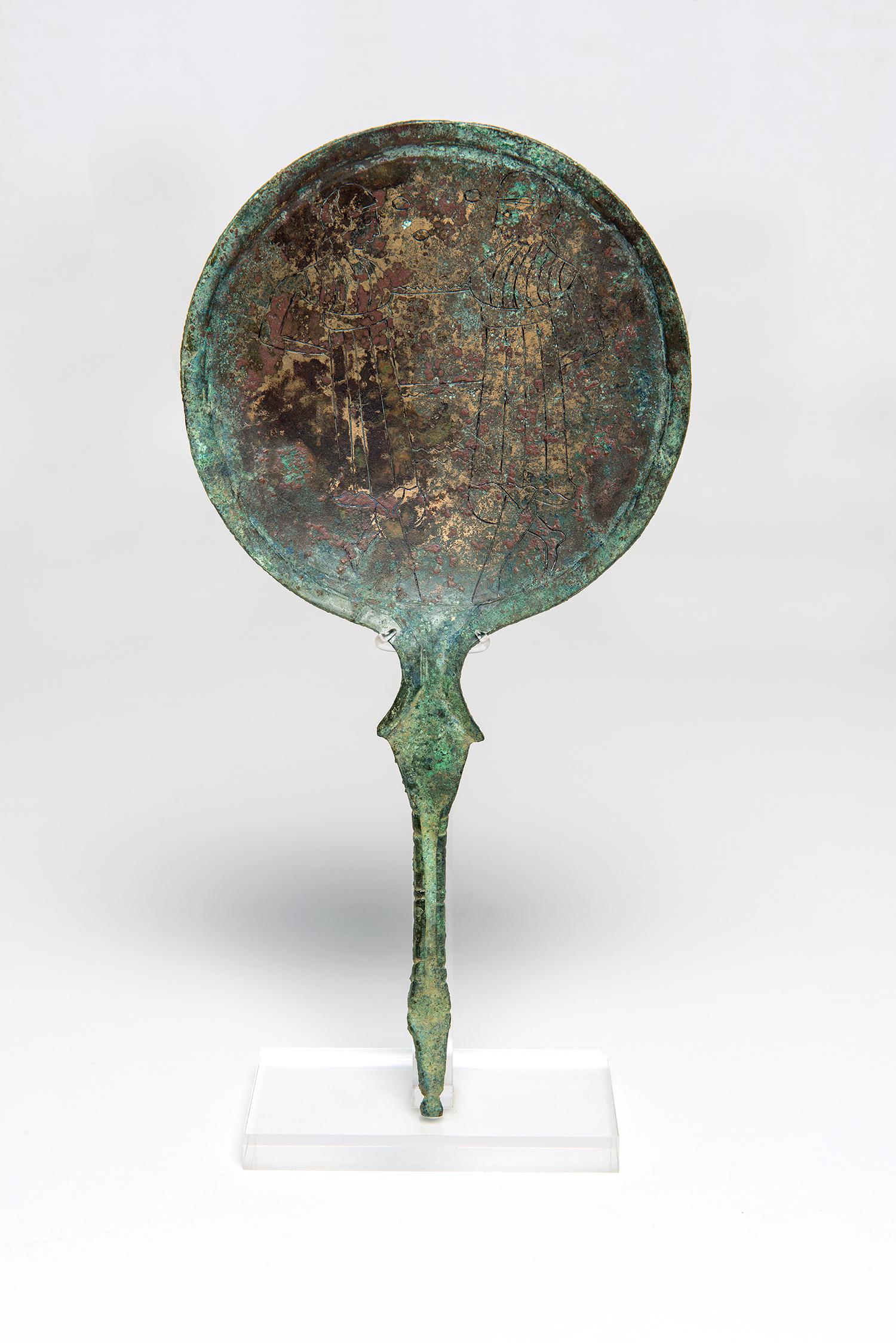 A wonderful Etruscan bronze mirror from the 2nd to 3rd century B.C., depicting two gods.
Obverse: Blue-green patina, bronze revealed in places. 
Reverse: blue-green patina. 
In the tondo two Dioskouroi wearing Phrygian caps stand alone facing each