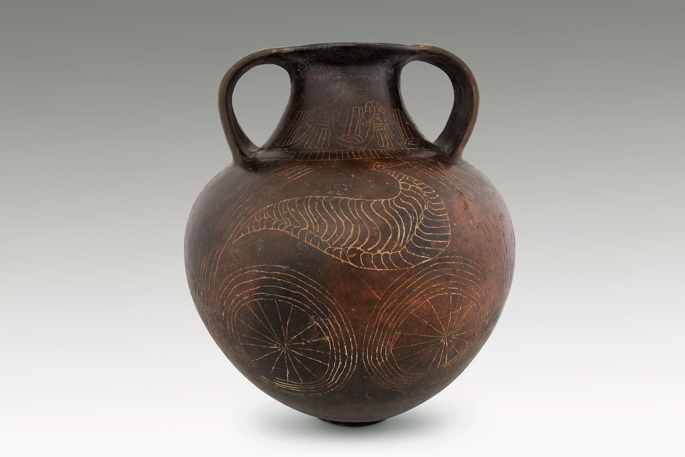 This highly important Etruscan amphora has two flattened handles that are elegantly placed on the shoulders to connect with the vessel’s rim. Both on the front and on the reverse a large stylized bird is placed over a pair of wheel shaped motifs. In