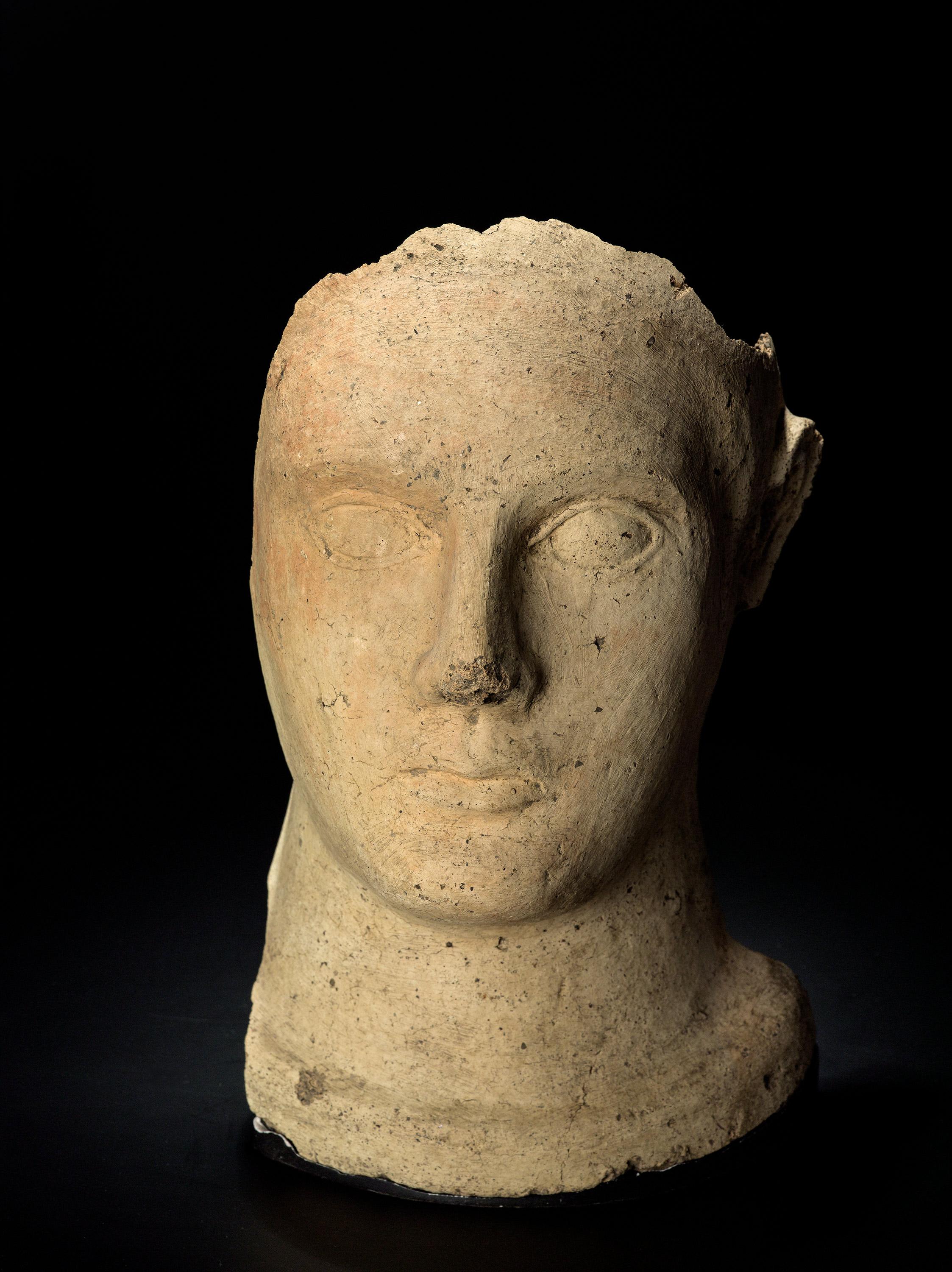 This fragment shows the frontal part of a male head with wide open eyes. The mouth is small which gives the face a severe and devote expression. The votive head is attributed to Veii, a walled Etruscan settlement on Isola Farnese that is situated