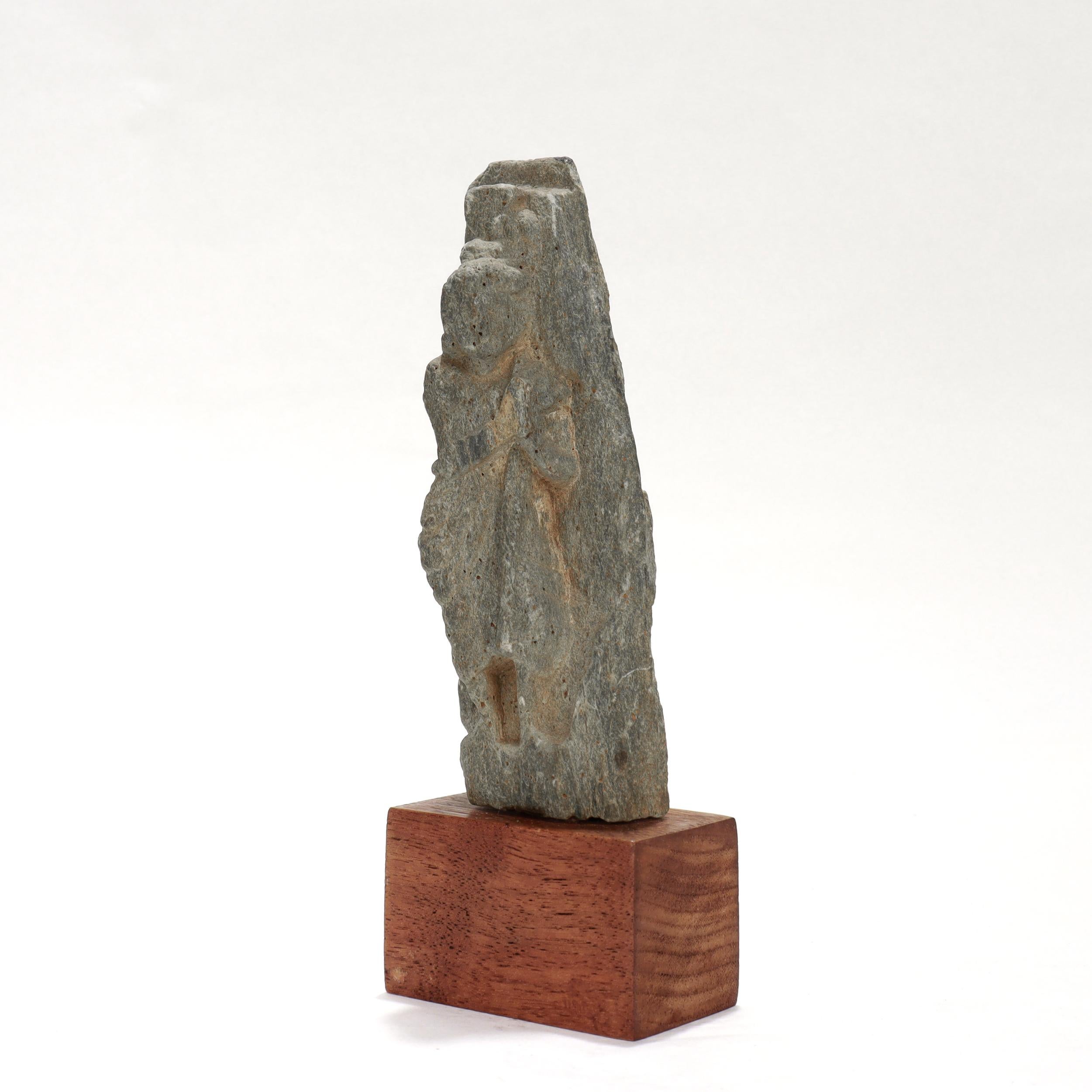 A fine ancient Ghandaran sculpture of the Buddha.

In green schist.

Depicting the Buddha carved in a standing position with his hands together, possibly in walking meditation or prayer.

Mounted onto a wooden rectangular plinth.

Simply a wonderful