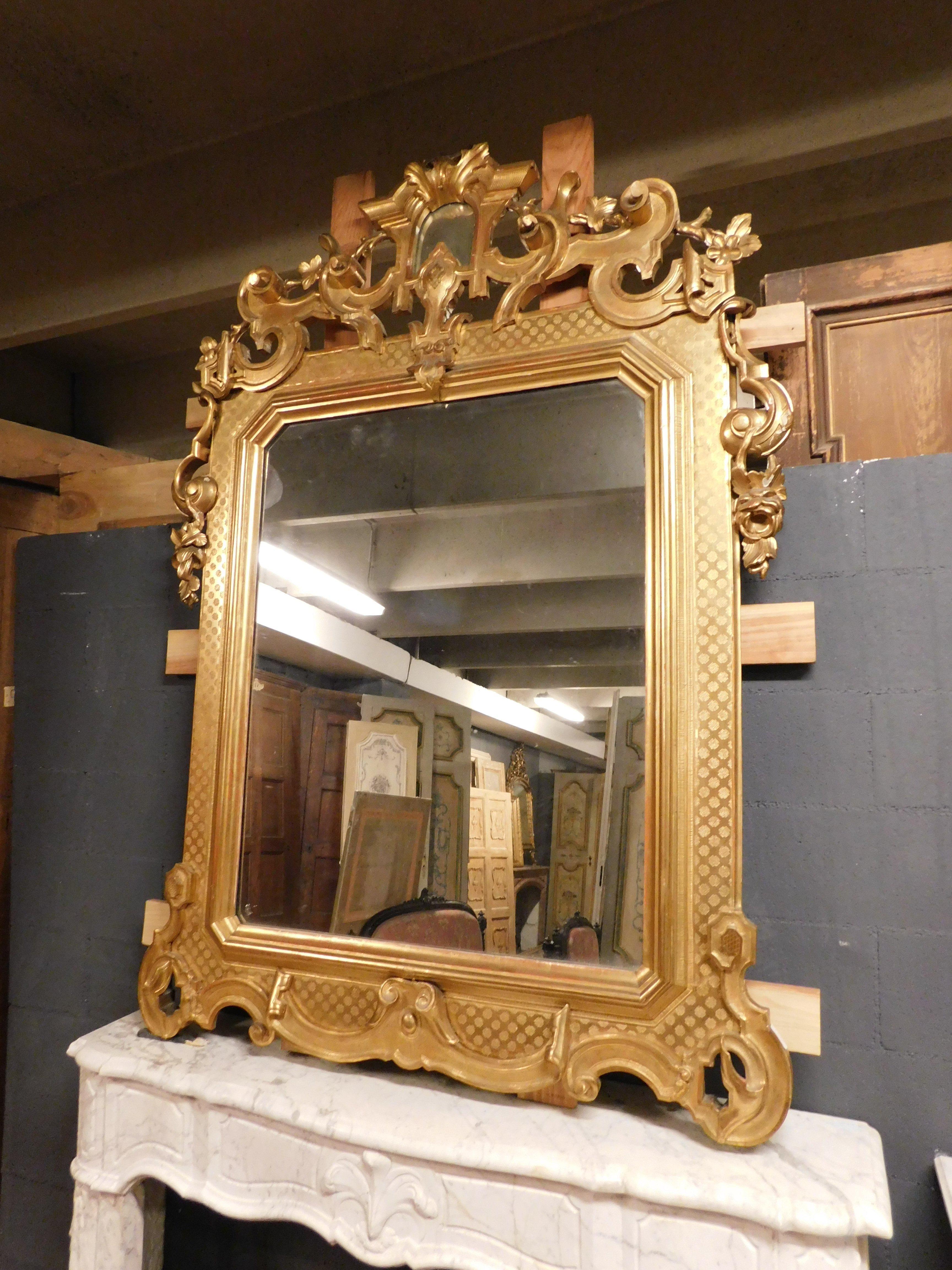 Ancient gilded and richly carved mirror, with decorated cymatium and frame carved in low relief, very elegant and refined, built to rest over a fireplace in the late 1800s in Italy.
External maximum size cm W 135 x H 186.