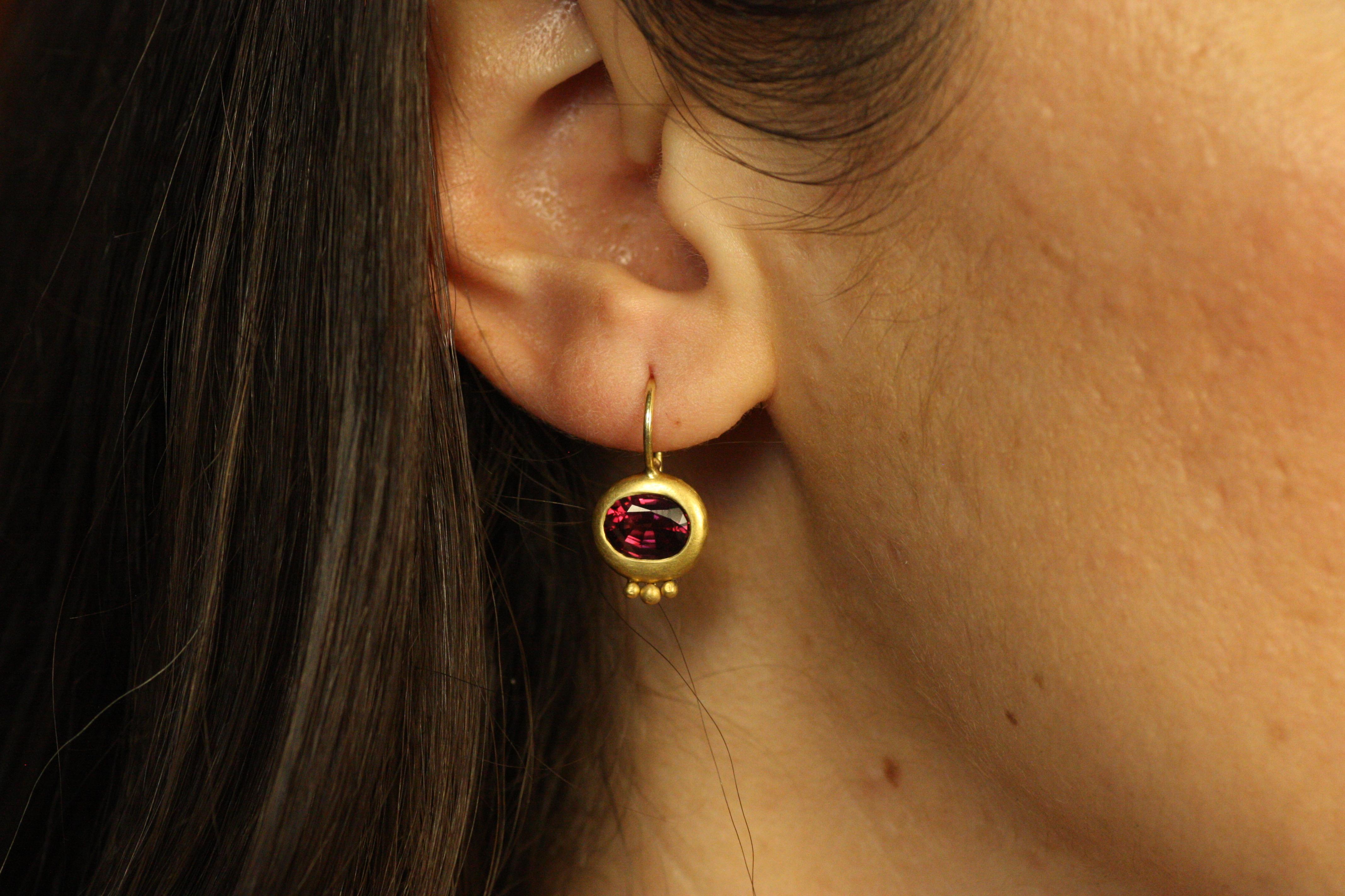 The Greco Earrings in 22K gold with faceted garnets offer a sophisticated design inspired by ancient elegance. Each bezel-set garnet stone boasts a rich, deep red hue that contrasts beautifully with the warm, lustrous gold. These handcrafted