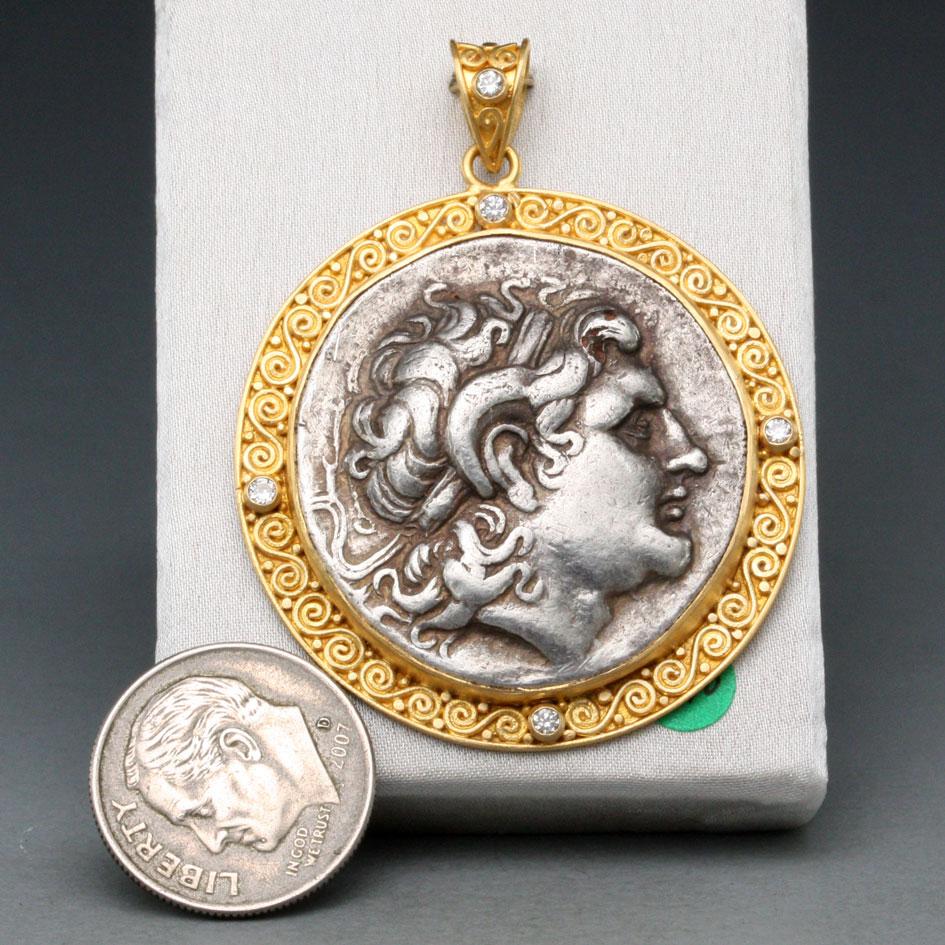 A high-grade authentic ancient silver tetradrachm coin from Thrace (a historical region which now encompasses parts of Greece, Bulgaria and Turkey) minted in 297-281 BC, with a depiction of Alexander the Great  is set in a handmade 22K gold