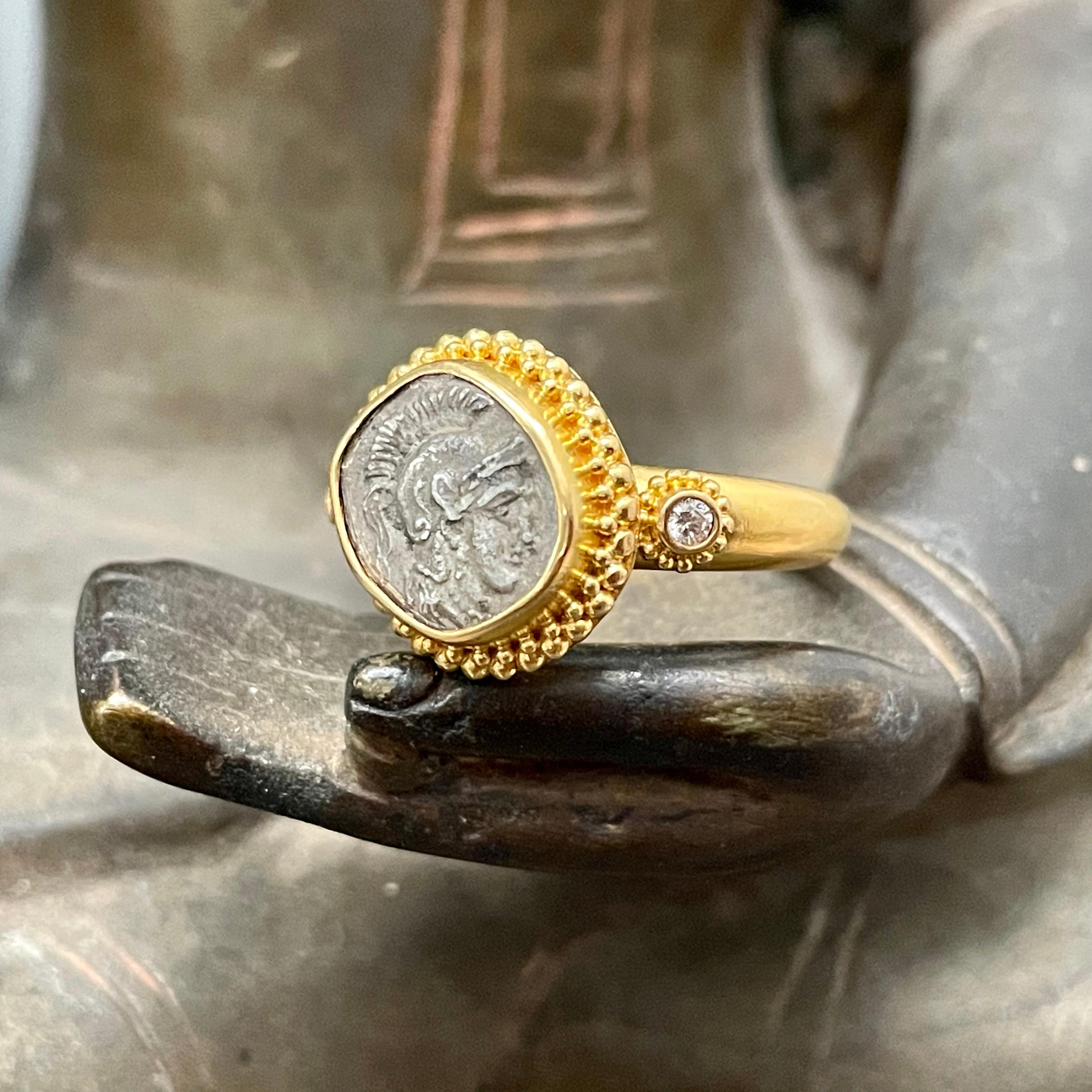 An authentic ancient Greek coin displaying a helmeted Athena from 333-323 BC is beautifully set in this Steven Battelle designed 22K gold ring. The coin is a silver 