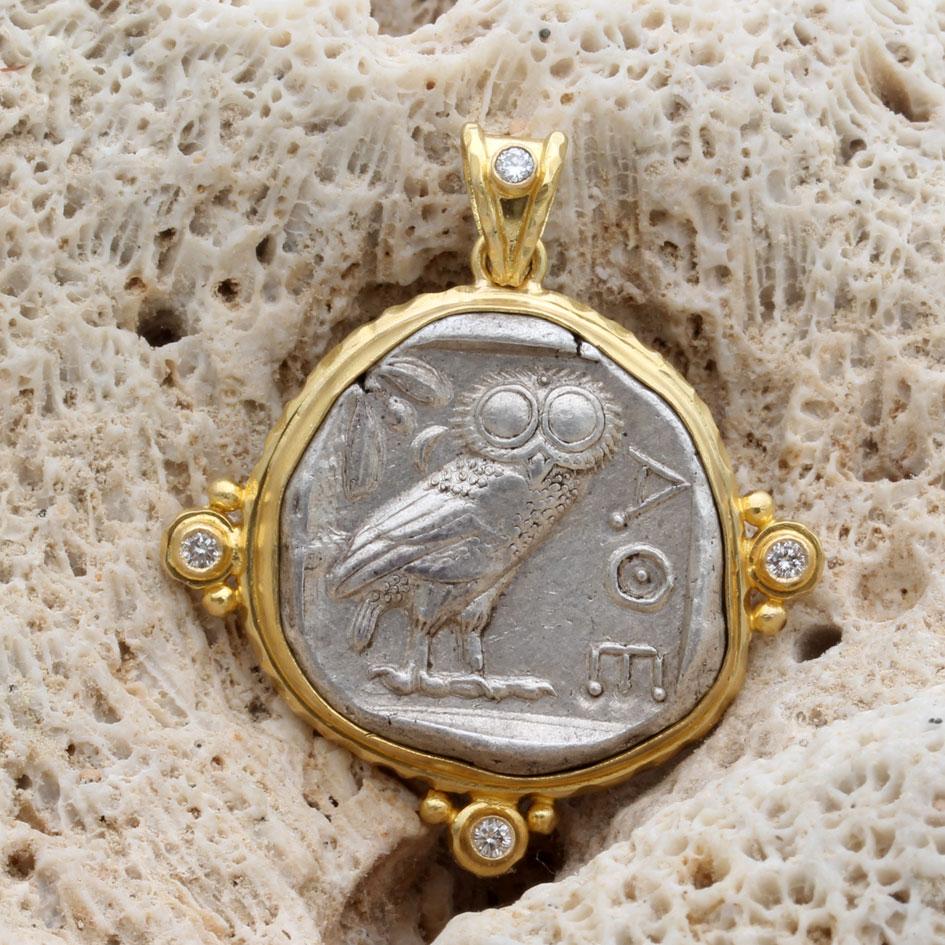 An iconic ancient Greek Athenian owl coin from 475-425 BC is held in a handmade hammered 18K gold bezel surrounded by a 