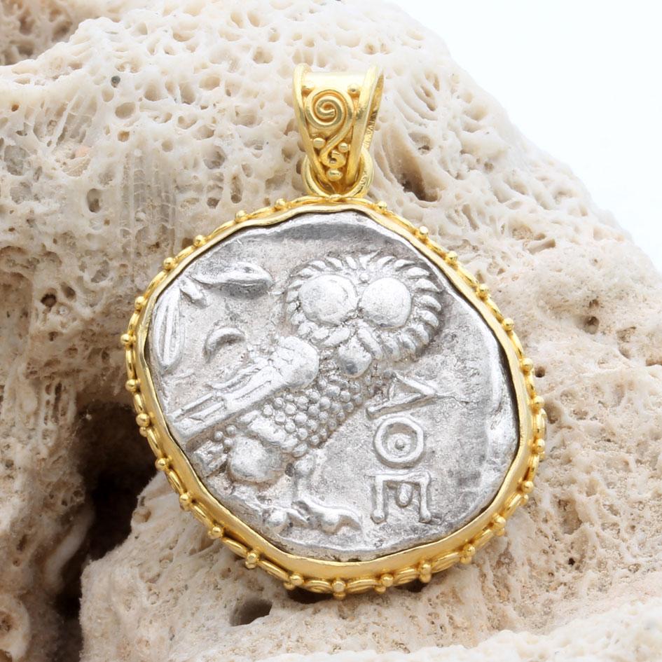 Una icónica moneda de búho de la antigua Grecia ateniense se abraza en pequeñas espirales aplicadas a mano de 18 quilates en este diseño de colgante de la firma Steven Battelle.  Las 