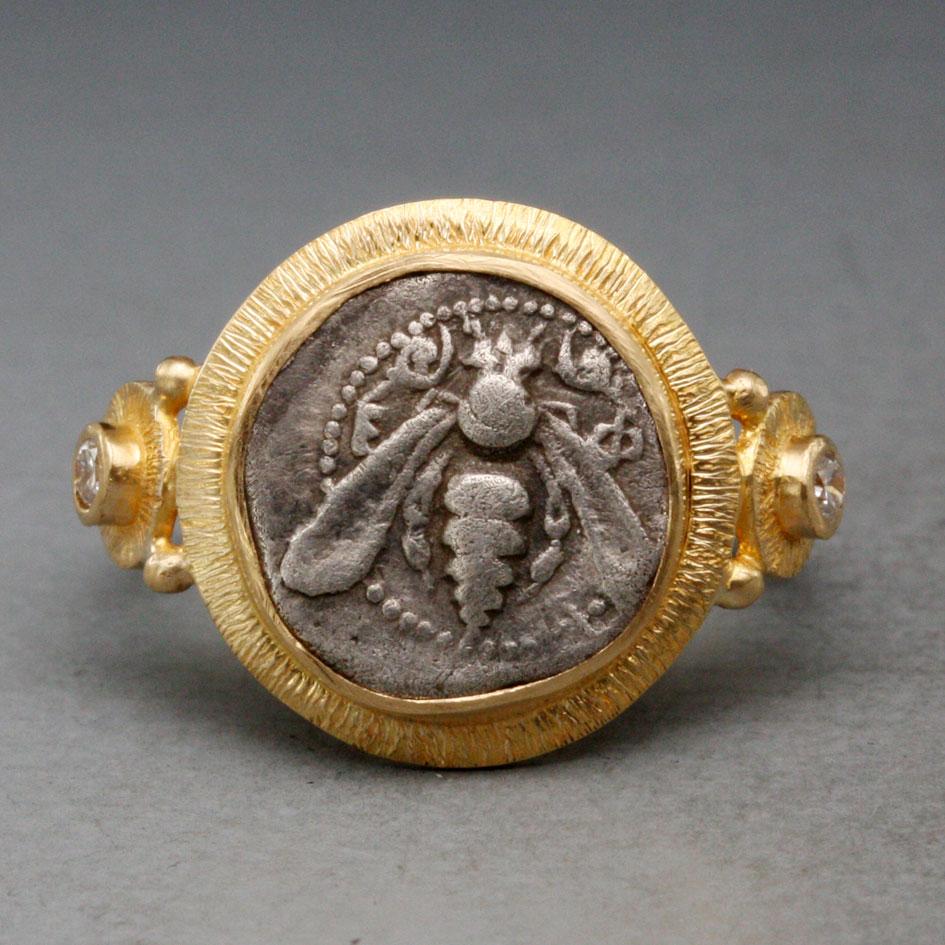 A very old  (520-400 BC) authentic ancient Greek coin from the Greek colony of Ephesus (currently in Turkey) is set highlighted by a lined texture bezel with two 1.8 mm VS1 accent diamonds accents flanking in this ancient- inspired Steven Battelle