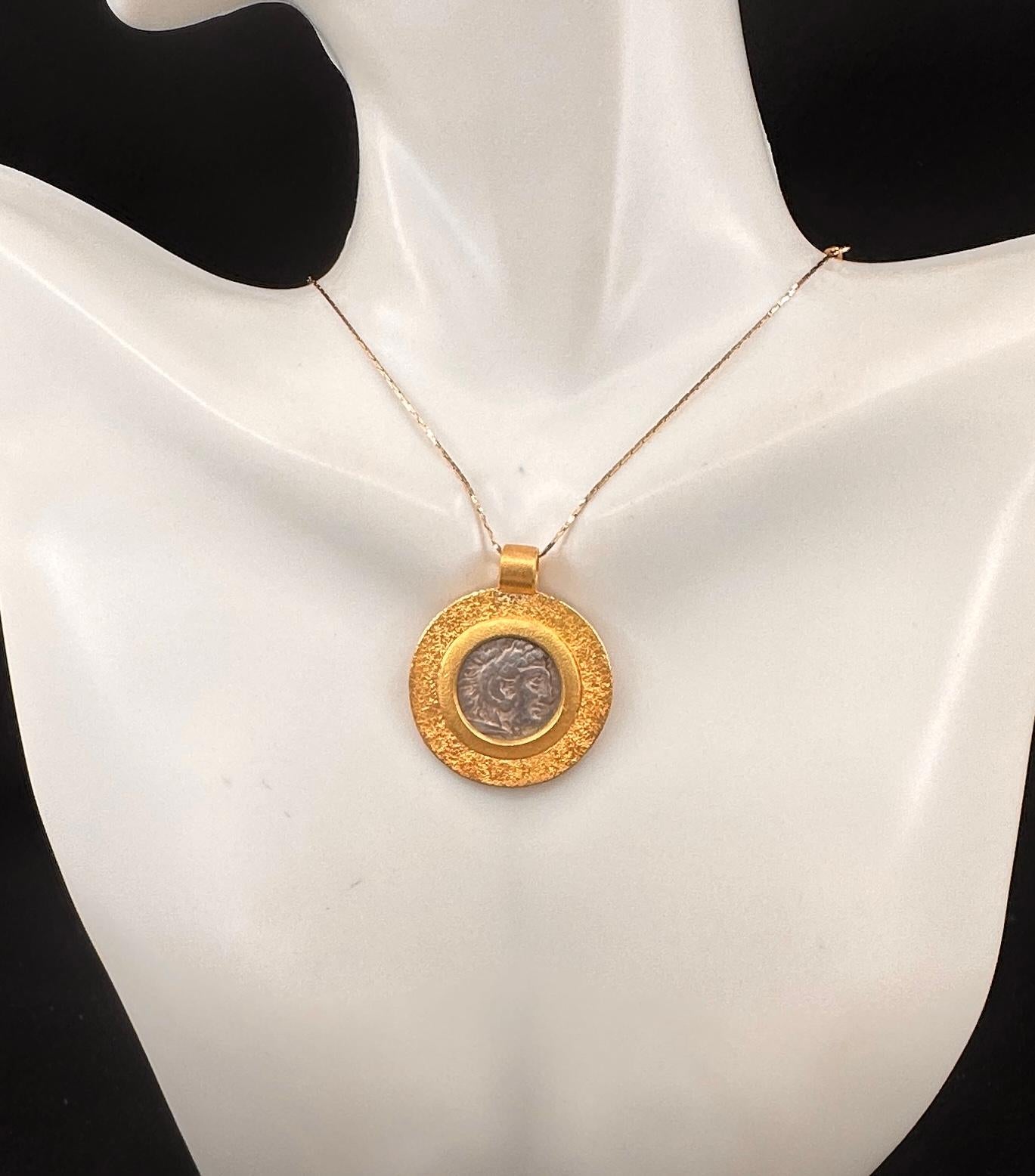 Adoptez l'élégance de la Grèce antique avec cet exquis collier pendentif en or 22 carats orné d'une pièce de monnaie grecque ancienne en drachme d'argent représentant Alexander le Grand d'un côté et Zeus trônant de l'autre.  La pièce grecque antique