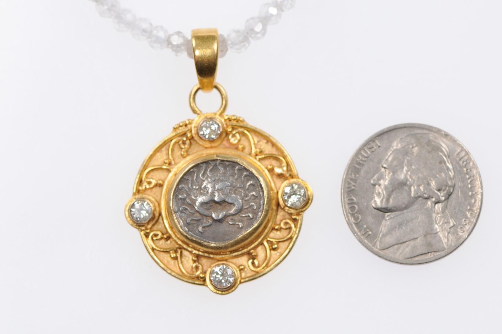 An authentic Greek Apollonia Pontika, AR Drachm Coin (late 5th-4th centuries BC), which has been artisan set within a custom 22-karat gold bezel, with a thick perimeter surround which is adorn with gold scrolls and beads. Decorative accent diamonds