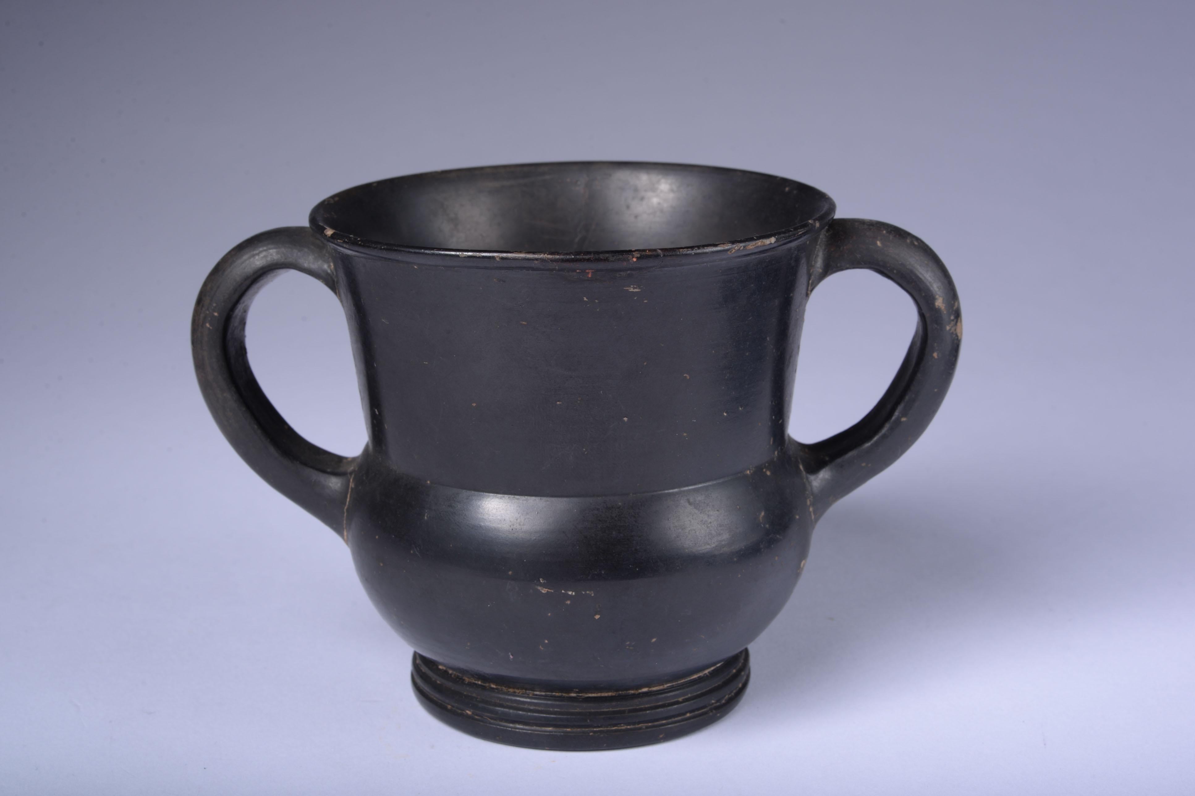 Greek Black Glaze Kantharos
Circa Early 4th Century B.C.
Terracotta
With old label reading ‘No. 133’
Height: 8.8 cm

This 4th Century B.C. kantharos is a wonderful example of the refined simplicity that characterises the artistic achievements
