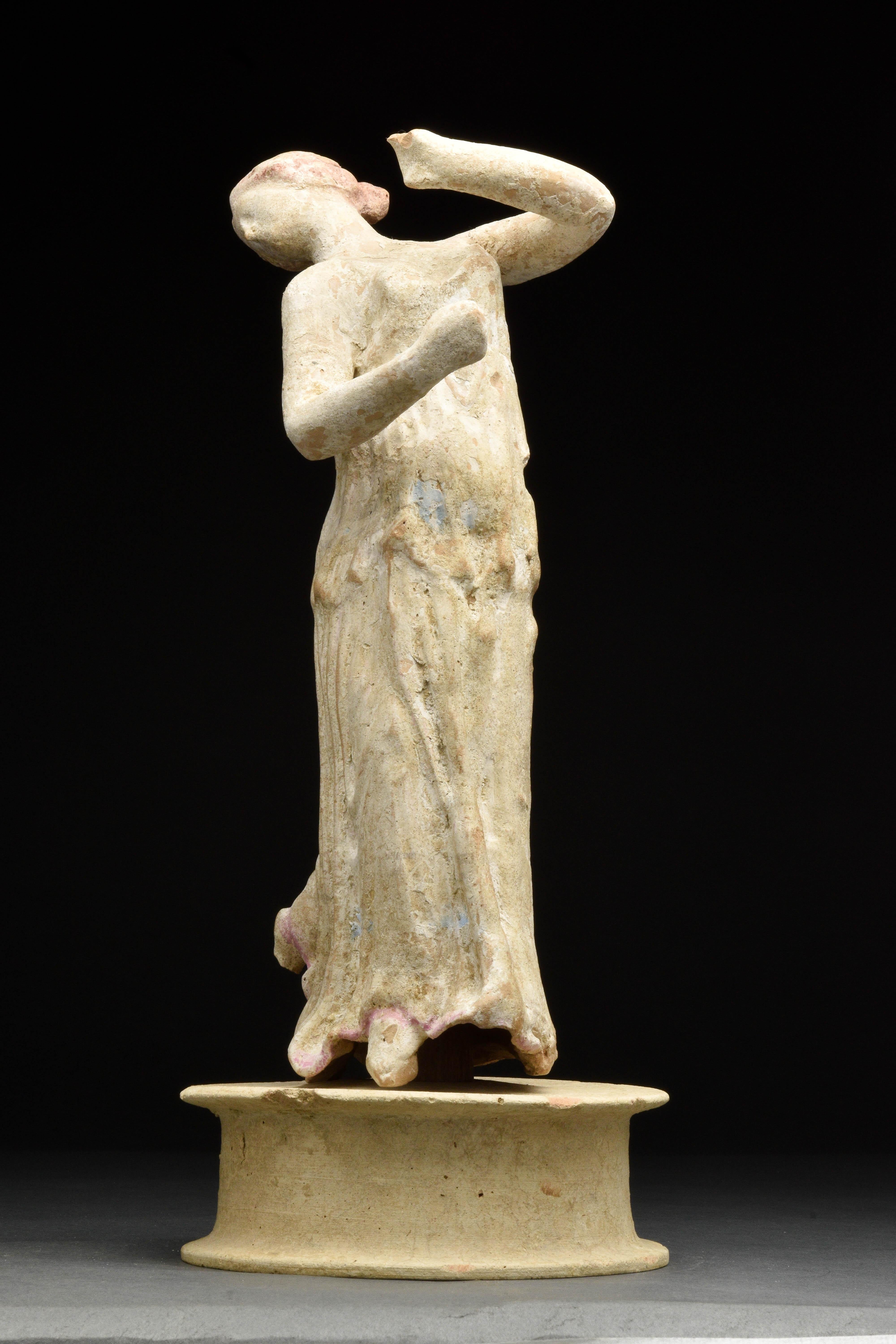 Circa 200 BC 
An ancient Greek Canosan terracotta statuette, perhaps from centurpipe, Sicily. The piece depicts a woman wearing a chiton, her body twisting spirally to the right, head thrown back and turned sharply to her right. Left leg raised