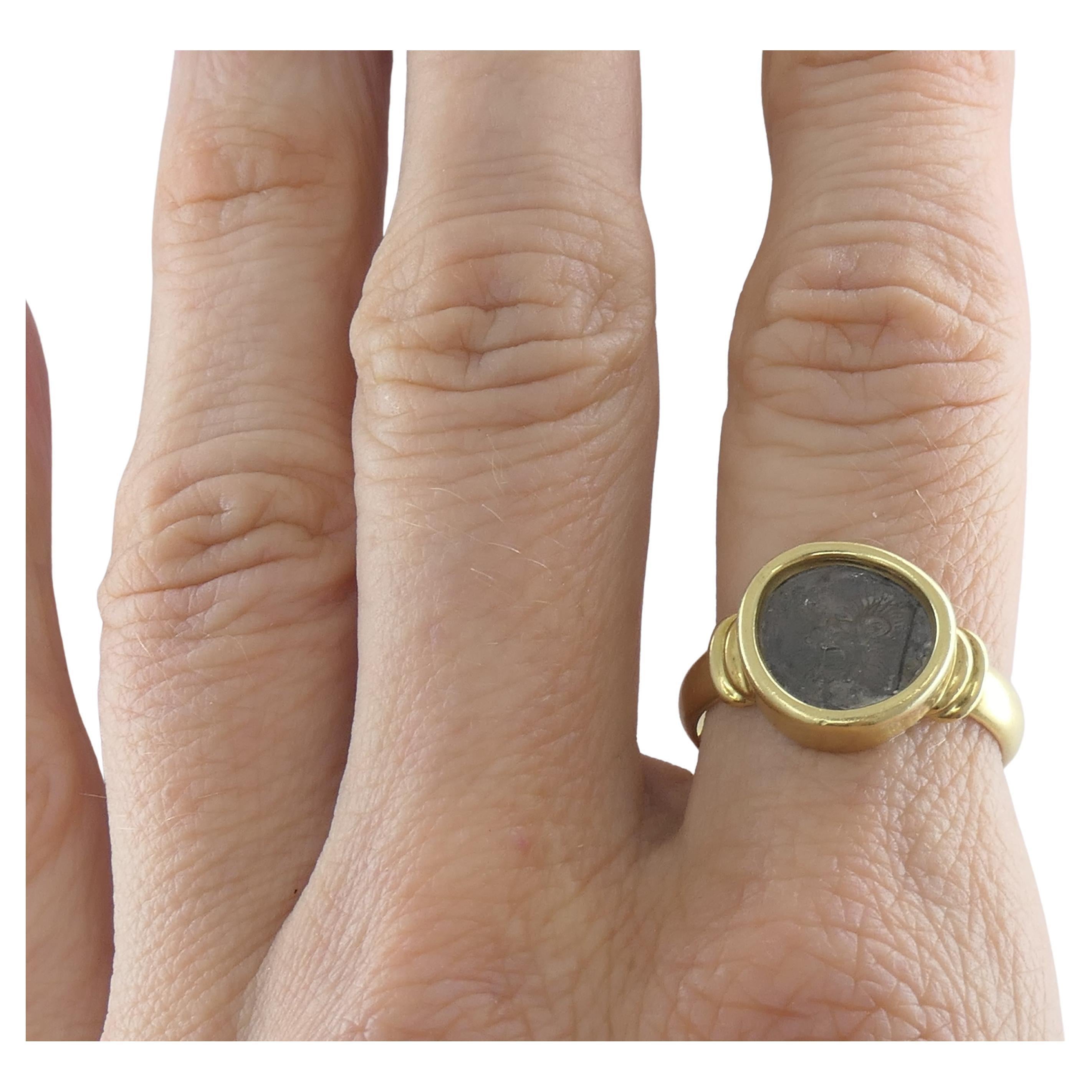 An ancient Greek coin ring made of 18k gold. 
The coin is a hemiobol from Kyzikos in Mysia 510-475 BC. The coin's averse is a stylized lion's roaring head and the reverse is a forepart of boar with a fish above. 
Founded in the mid-8th century B.C.