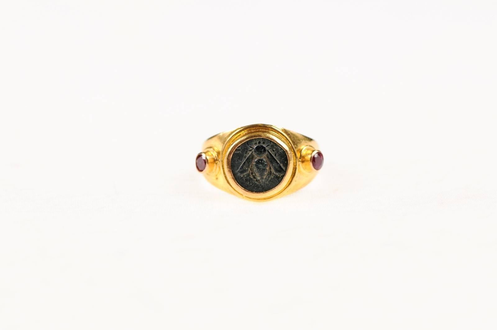 An authentic ancient Greek bronze coin from Ephesos, Ionia (circa 400-300 BC) custom mounted within a 22-karat gold band and flanked with rubies. Ancient Greek coins from Ephesos (often spelled Ephesus), Ionia are from the region which would now be