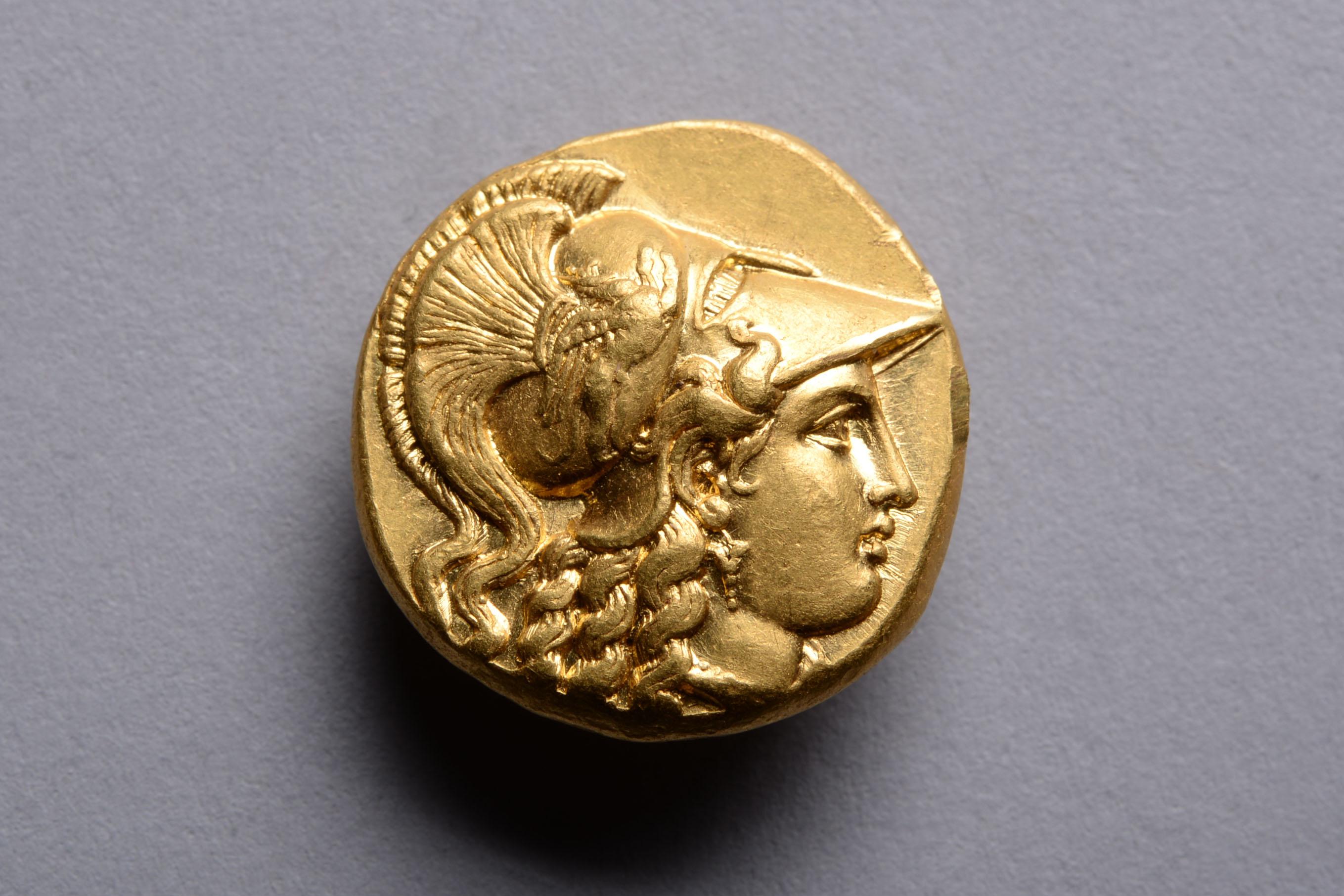 A gold stater issued in the name of King Philip III of Macedon. Struck at the Babylon mint, 323 - 317 BC.
 
The obverse with the head of Athena, wearing a single drop earring and Corinthian helmet decorated with a charging griffin below an