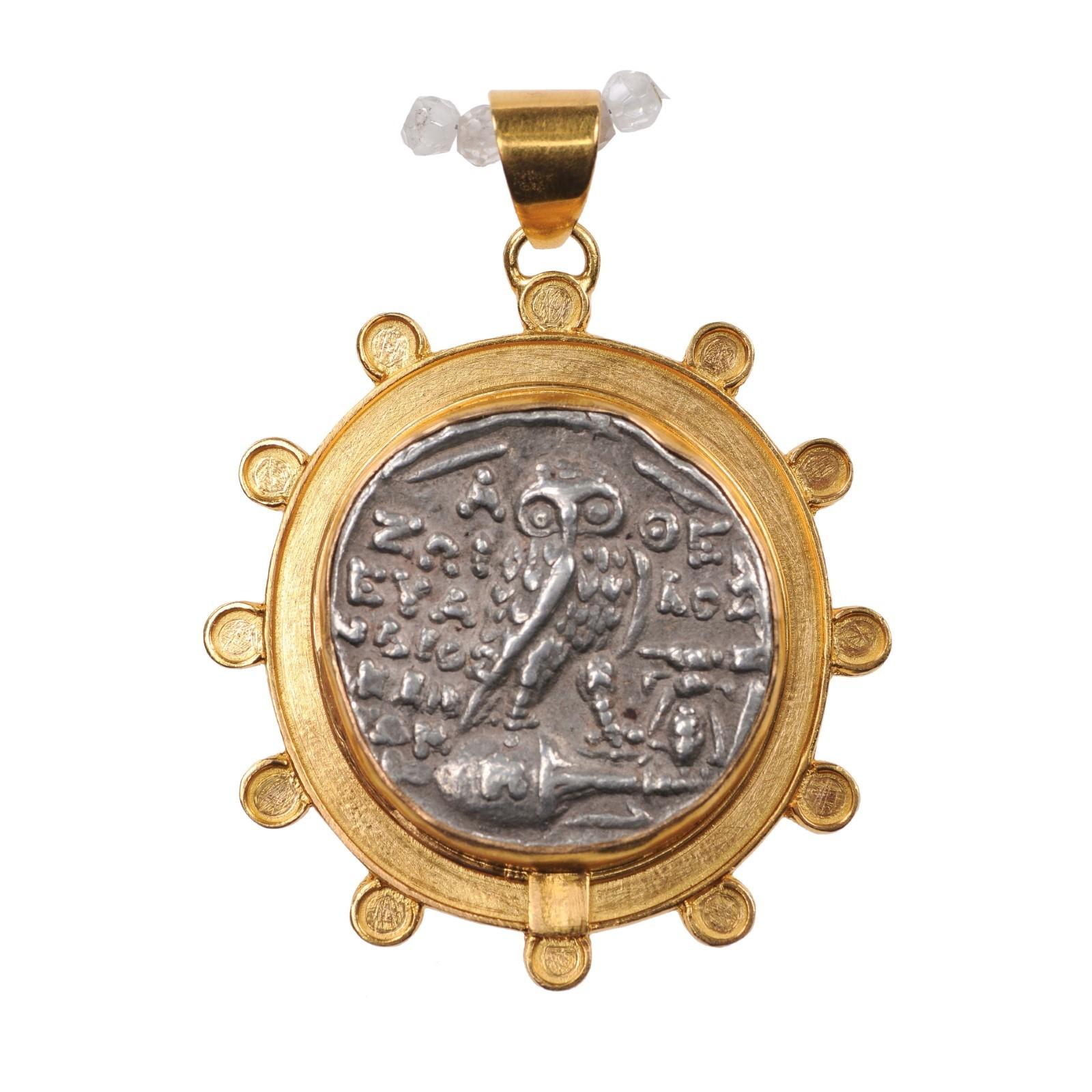 An authentic Greek, Athens silver tetradrachm coin of Athena and Owl (circa 109/108 BC), set in a custom 22-kt gold bezel embellished with round accents about the perimeter, and 22-kt gold bail. The obverse, or front side of this coin features the