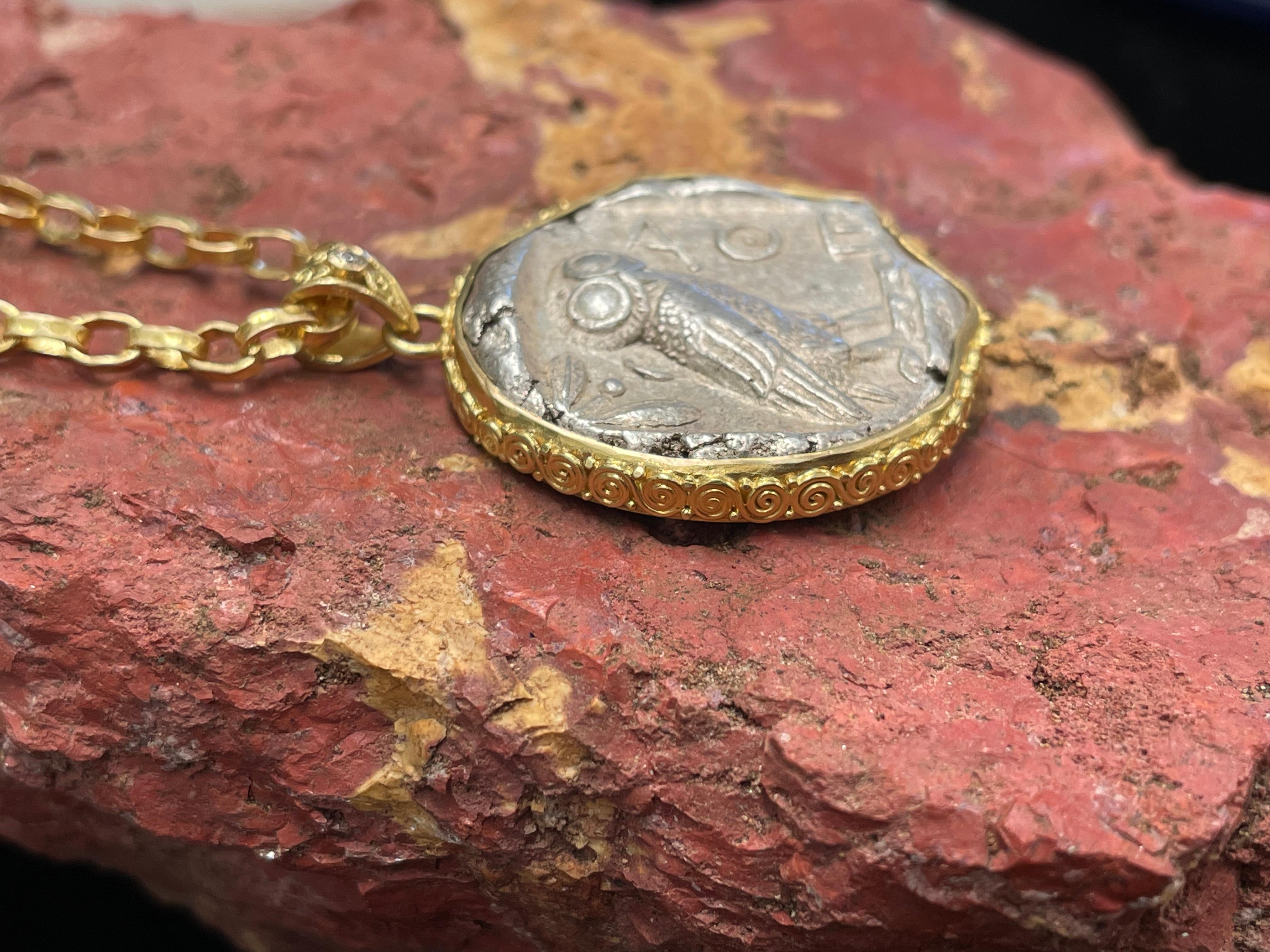 An iconic Ancient Greek Athenian owl coin from 475-425 BC is held in hand applied 18K small spirals embrace with a diamond accent in this signature Steven Battelle pendant design.

This coin from Athens, Attica, is a tetradrachm (4 drachms) which