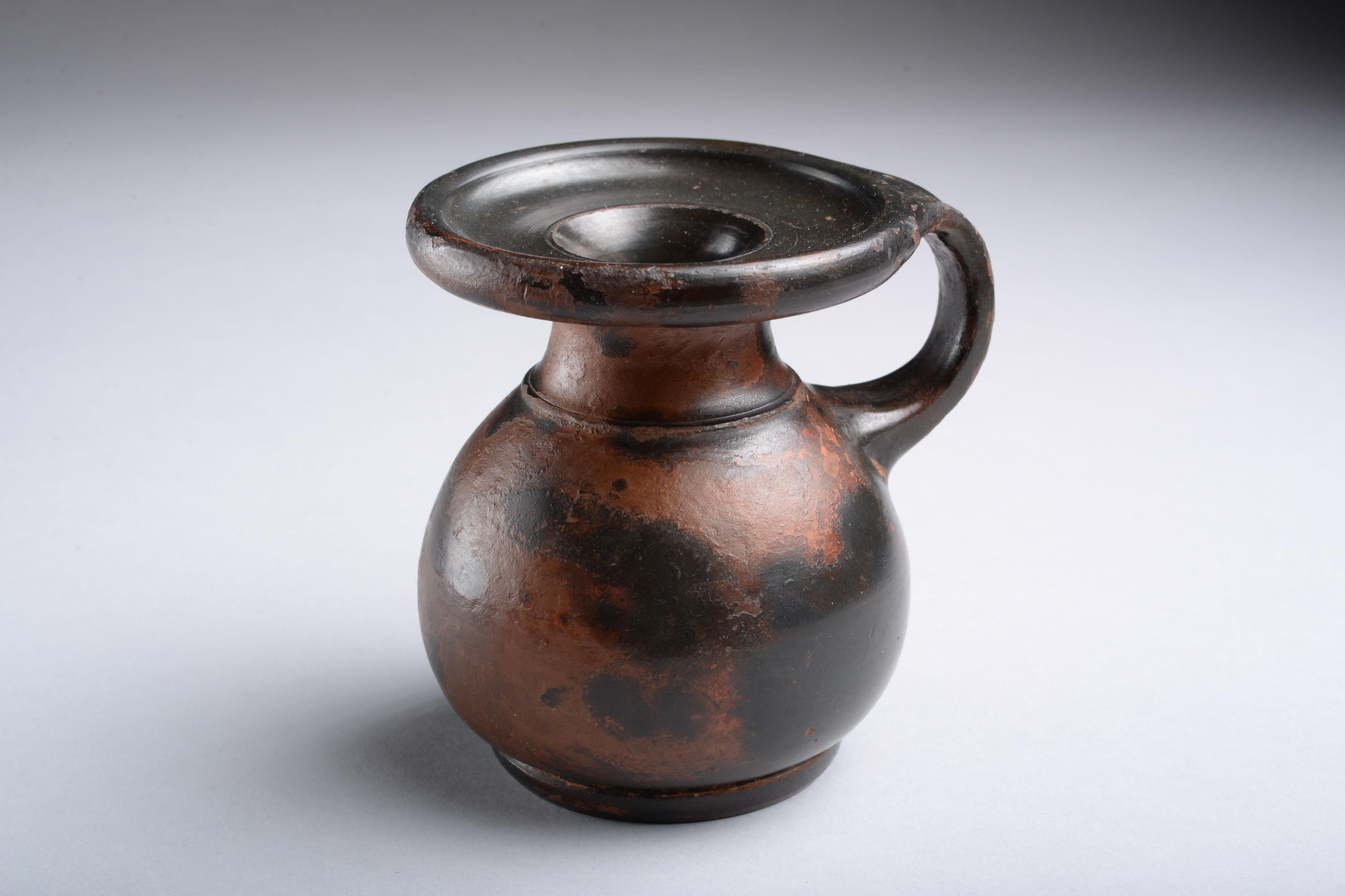Athenian Black-glaze perfume pot with inscription
Athens, c. 425-400 B.C.
Terracotta
Measures: Height: 9cm; diameter across lip: 7.5cm; width including handle: 9cm

This 5th Century B.C. perfume pot from Athens is a fine testament to the