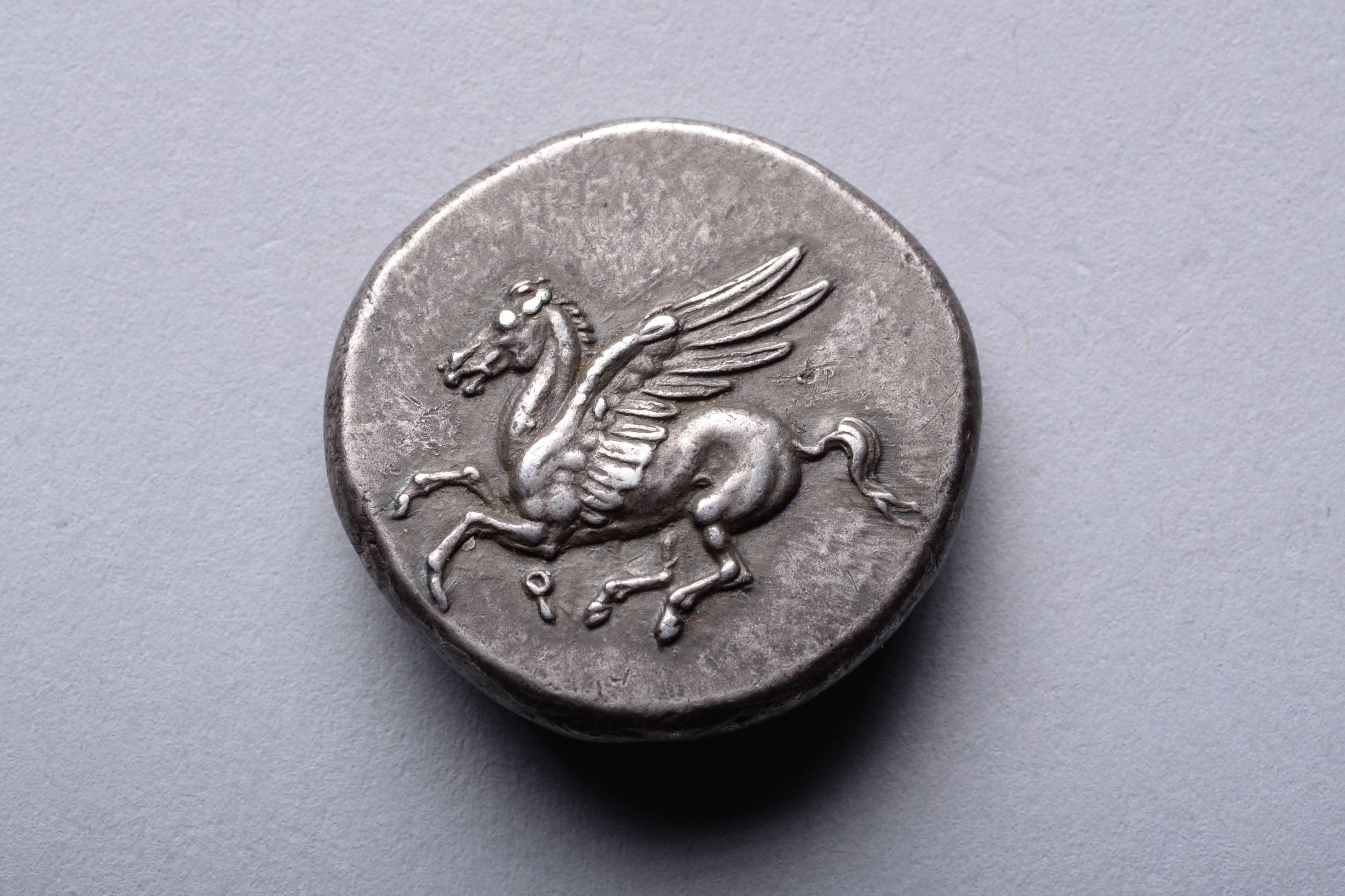 A silver stater from Corinth, circa 345-307 BC.

The obverse with Pegasus in flight. 

The reverse with the head of Athena, shown wearing a beaded necklace and Corinthian helmet, decorated with a laurel wreath. Aegis with Gorgon's head and A P