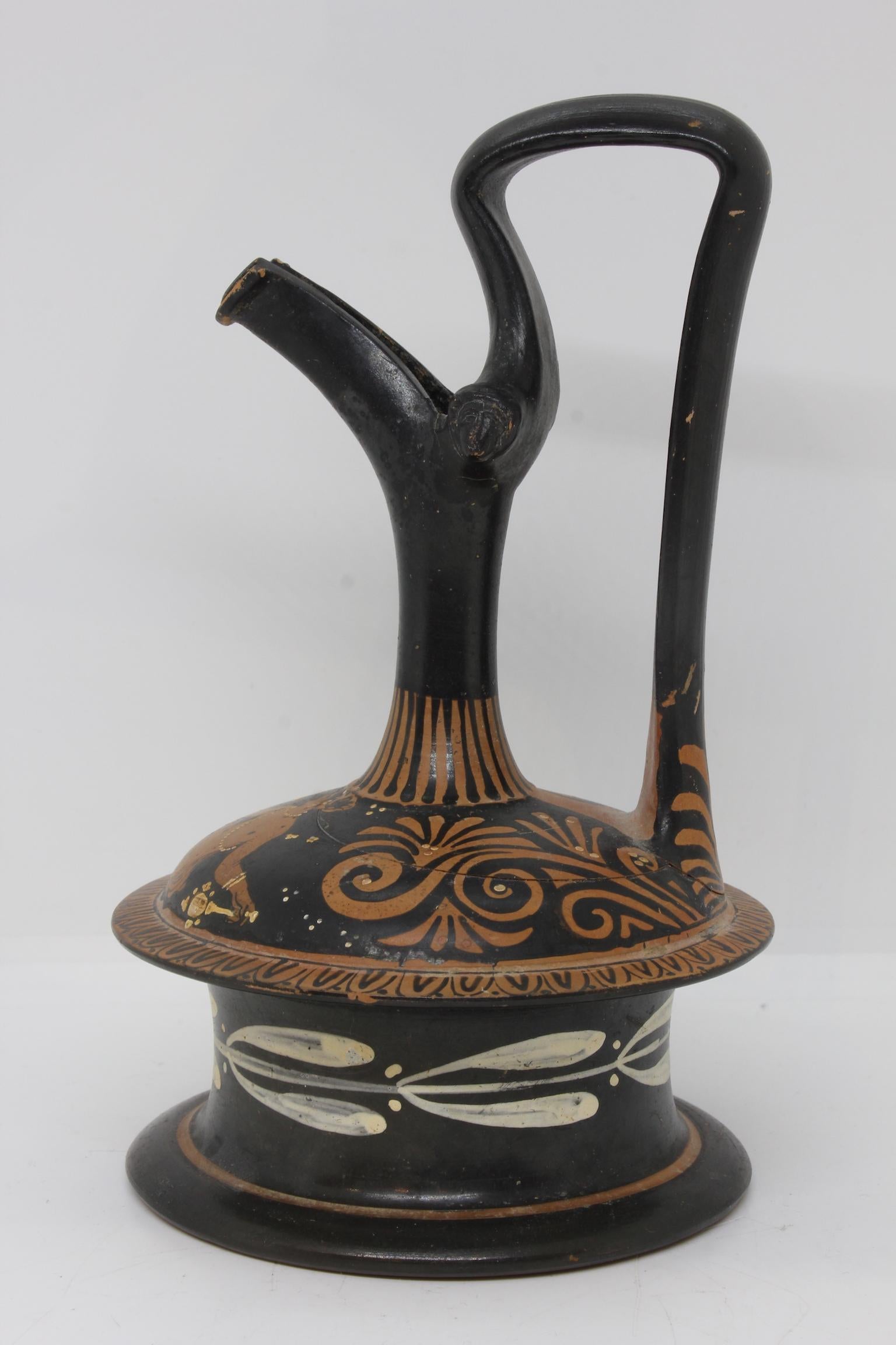Ancient Greek Epichysis in black glazed terracotta painted with a draped woman holding a plate and a mirror, Magna Graecia, 4th century BC.
Provenance: Purchased in a sales room in the 1980s. A certificate of authenticity by an archeology expert