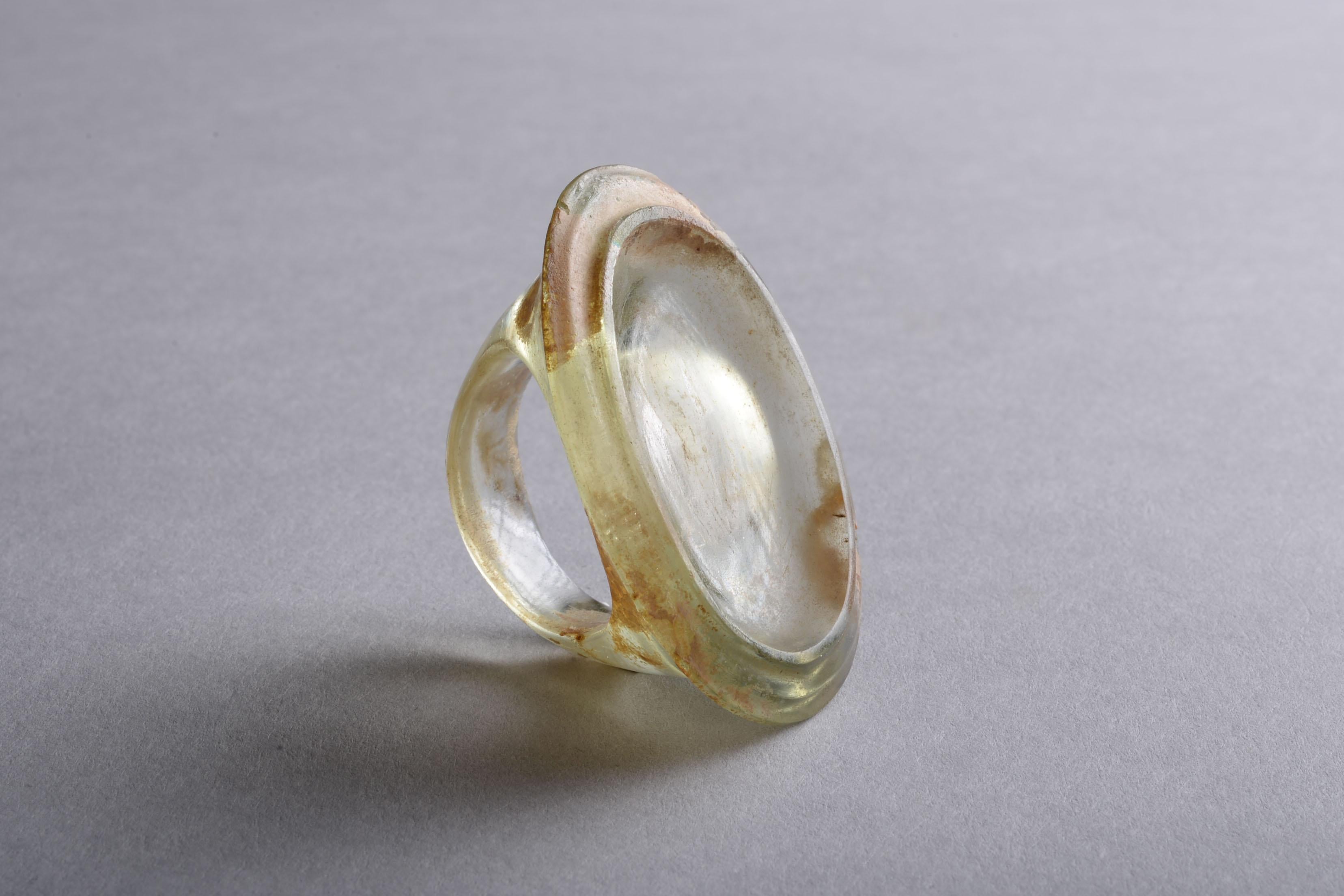 This beautifully preserved ring was cast from light green transparent glass. Its large size and shape are typical of Hellenistic finger rings, and its now empty oval bezel would originally have been decorated.

Jewellery was produced in abundance