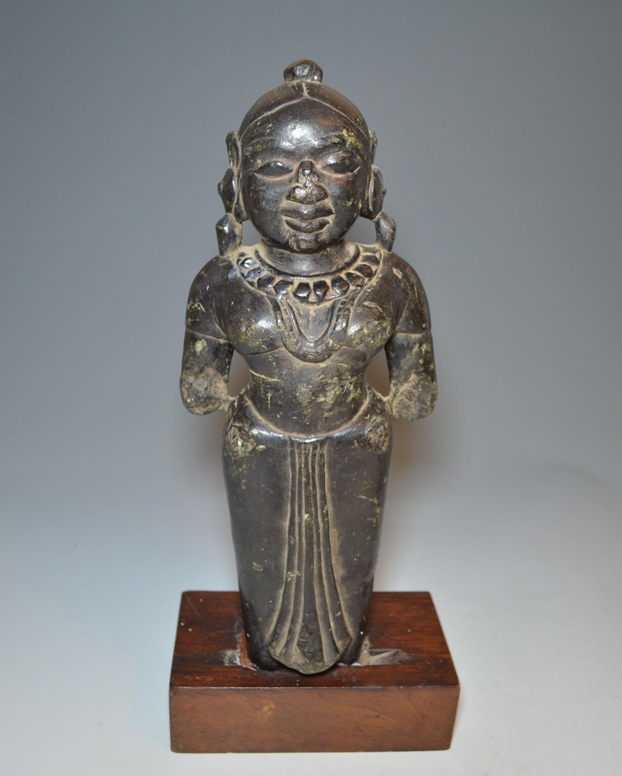 A rare Indian Hindu or Jain stone female Goddess or consort figure, circa 16th century
The stone female figure in green slate with darkened patina, a standing goddess or consort wearing necklaces and large earnings wearing a pleated skirt and