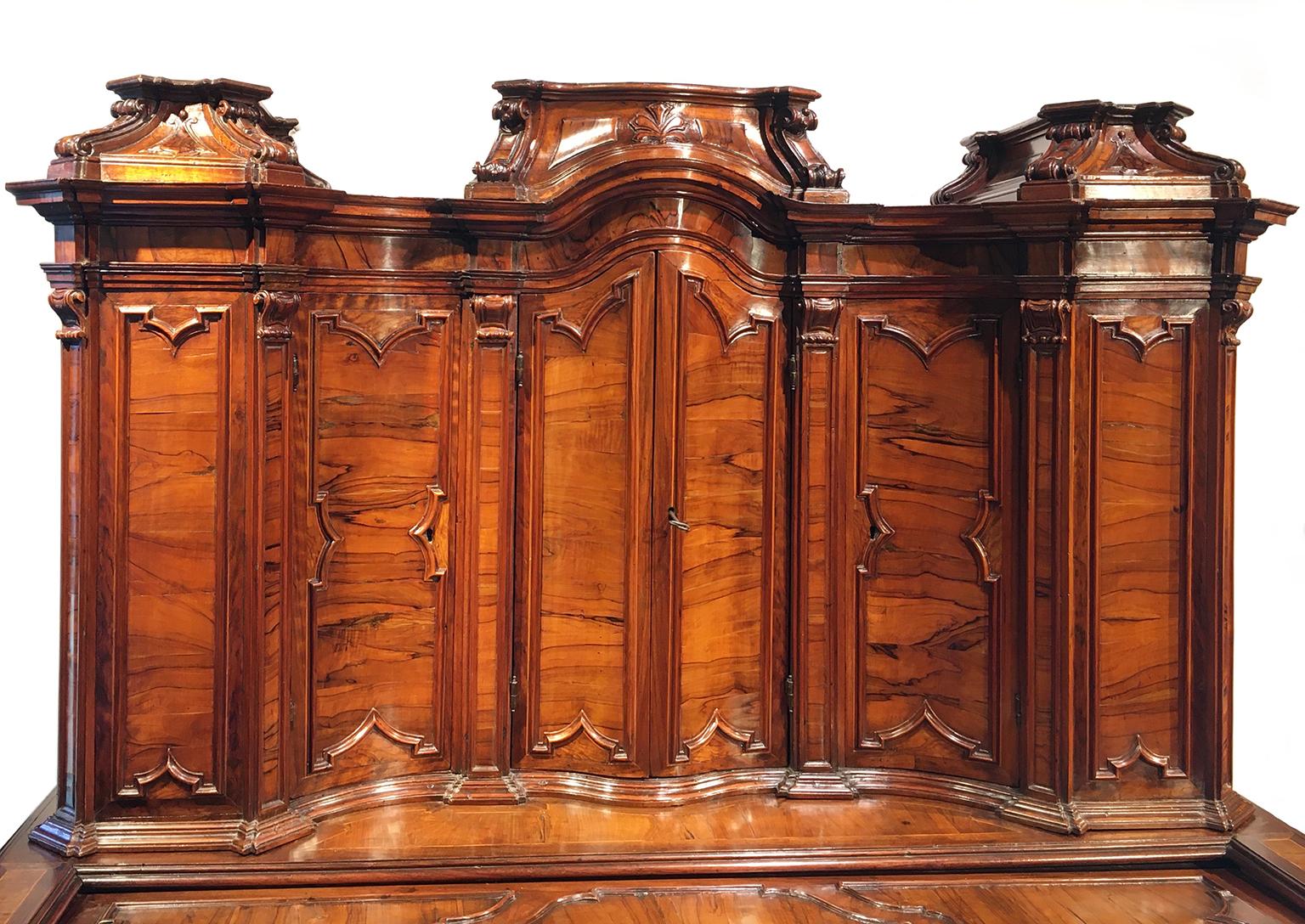 Writing desk with upper cabinet
Milan, first half of the 18th century 
Carved walnut partially veneered in olive wood and walnut burl; traces of ebonizing.
It measures 66.53 in x 48.42 in x 23.22 in (169 x 123 x 59 cm)
State of conservation: