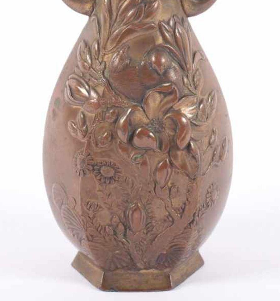 This Meiji vase is a beautifully decorated metal alloy vase, realized in Japan under the Meiji Empire (1867-1912).

Take a look at the relief decors, lions on the base of the handles and flowers on the round-body of the vase. The hexagonal base