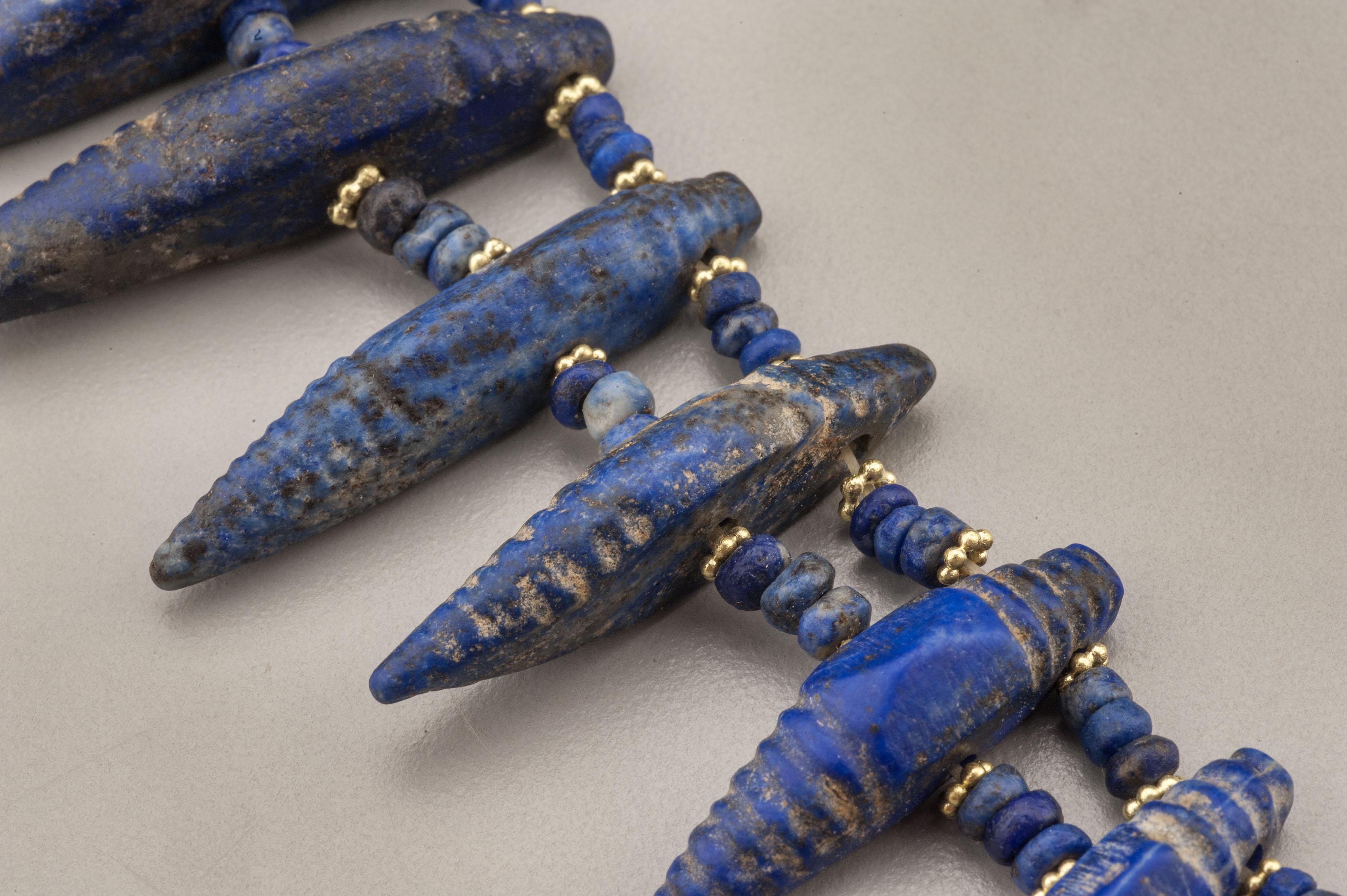 One hundred and seventy-one lapis lazuli beads, twenty-three of which are double drilled pendant beads of an elongated form. Each of these are faced with 22k gold granulated ring beads. There are ninety-two of these gold beads in the necklace. The