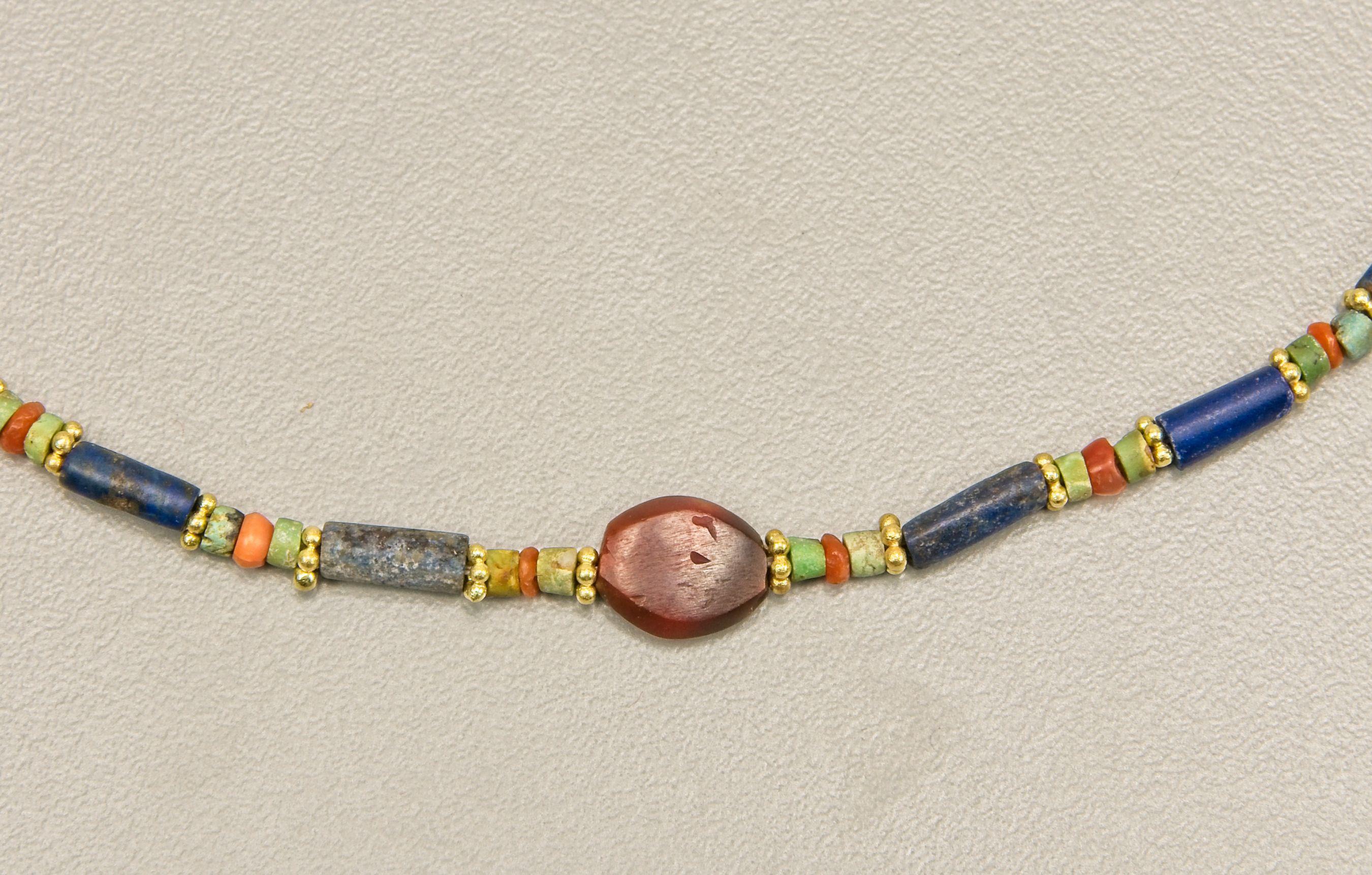 Lapis lazuli cylinder beads alternating with carnelian and turquoise disc beads and faced with granulated 20k gold ring beads. The necklace features a tabular carnelian bead in the center. This bead is 1 cm in length, 9 mm in width at the center and