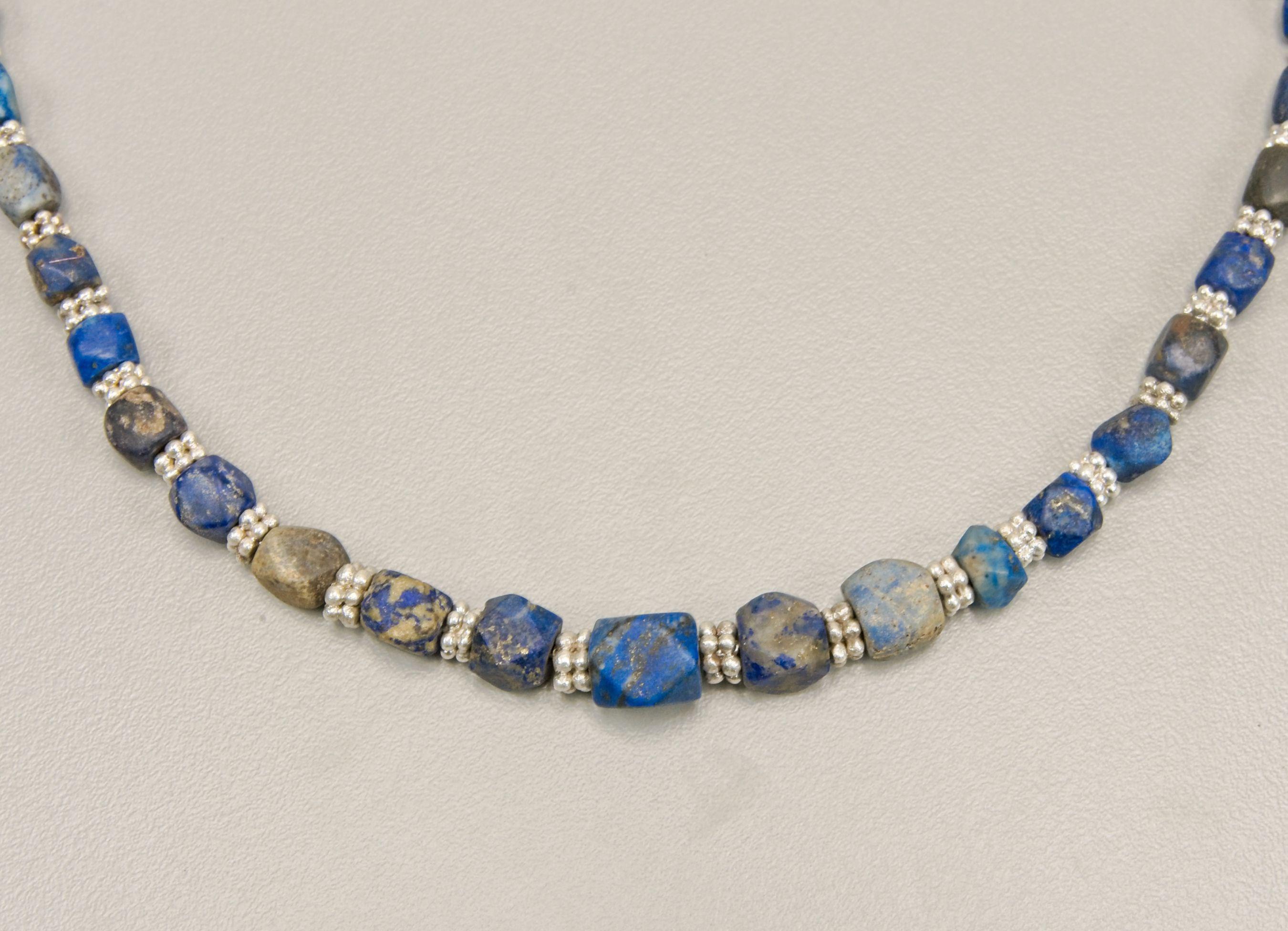 Forty-six ancient corner-less cube lapis lazuli beads alternating with two layer granulated silver ring beads. The beads graduate in size from the front to the back of the necklace. The center bead is 1.23 cm in length, 9.5 mm in width and has a