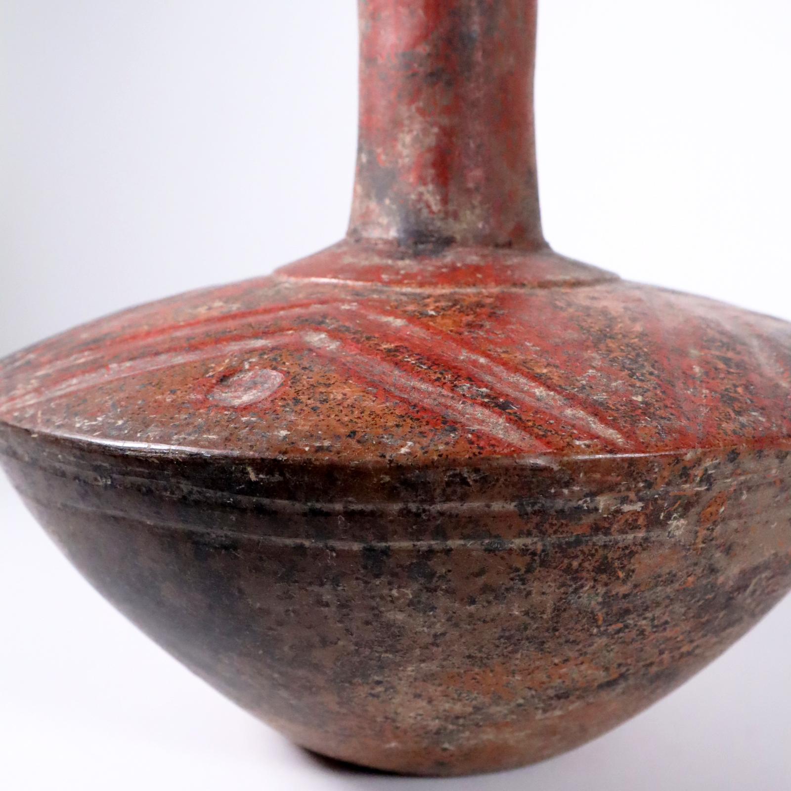 A simple, elegant long necked carinated jar from the site of Tlatilco, valley of Mexico. Burnished earthenware with tan and red slips. Attractive black manganese deposits on the surface indicating authenticity and age. Lightly grooved in a star