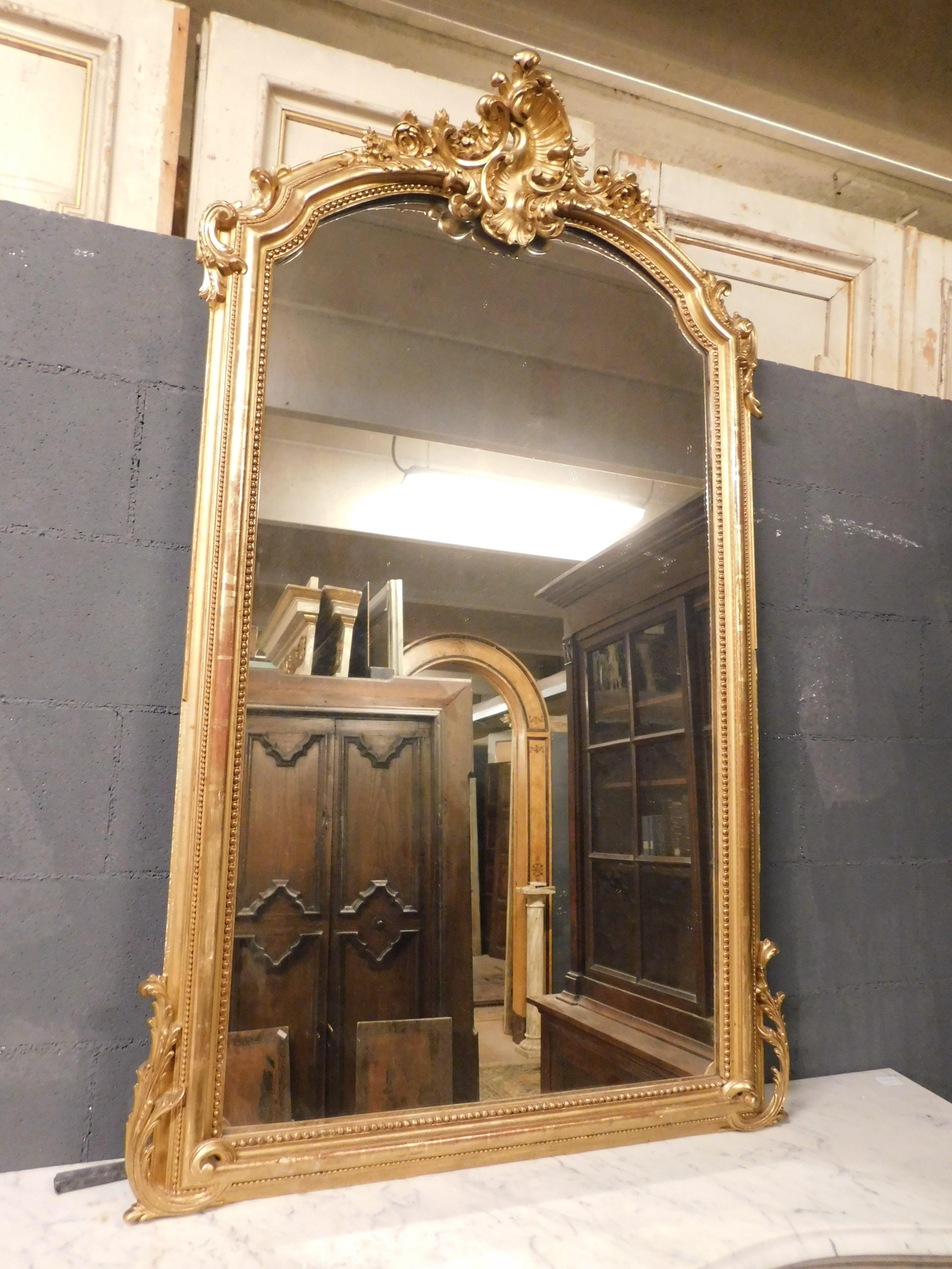 Antiker Spiegel aus vergoldetem Holz mit reich geschnitztem Fries, oben eine schöne Skulptur und Rüschen an den Seiten, gebaut im 19. Jahrhundert in Frankreich, er wurde über einem Kamin platziert, jetzt anpassbar auch als Eingangsspiegel oder über