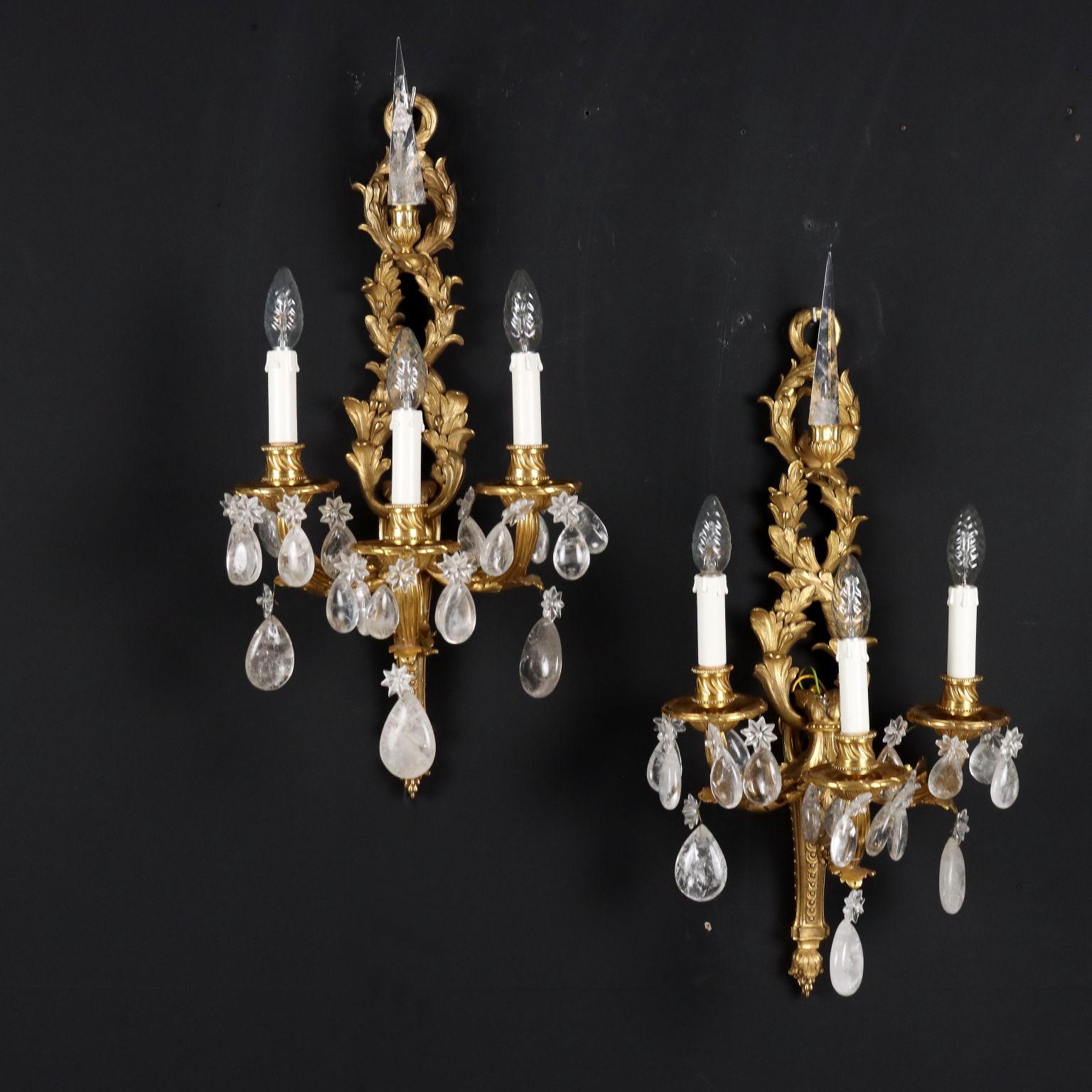 Pair of three-light wall sconces with gilded bronze frame, obelisk on top and rock crystal pendants. Italy 20th century.