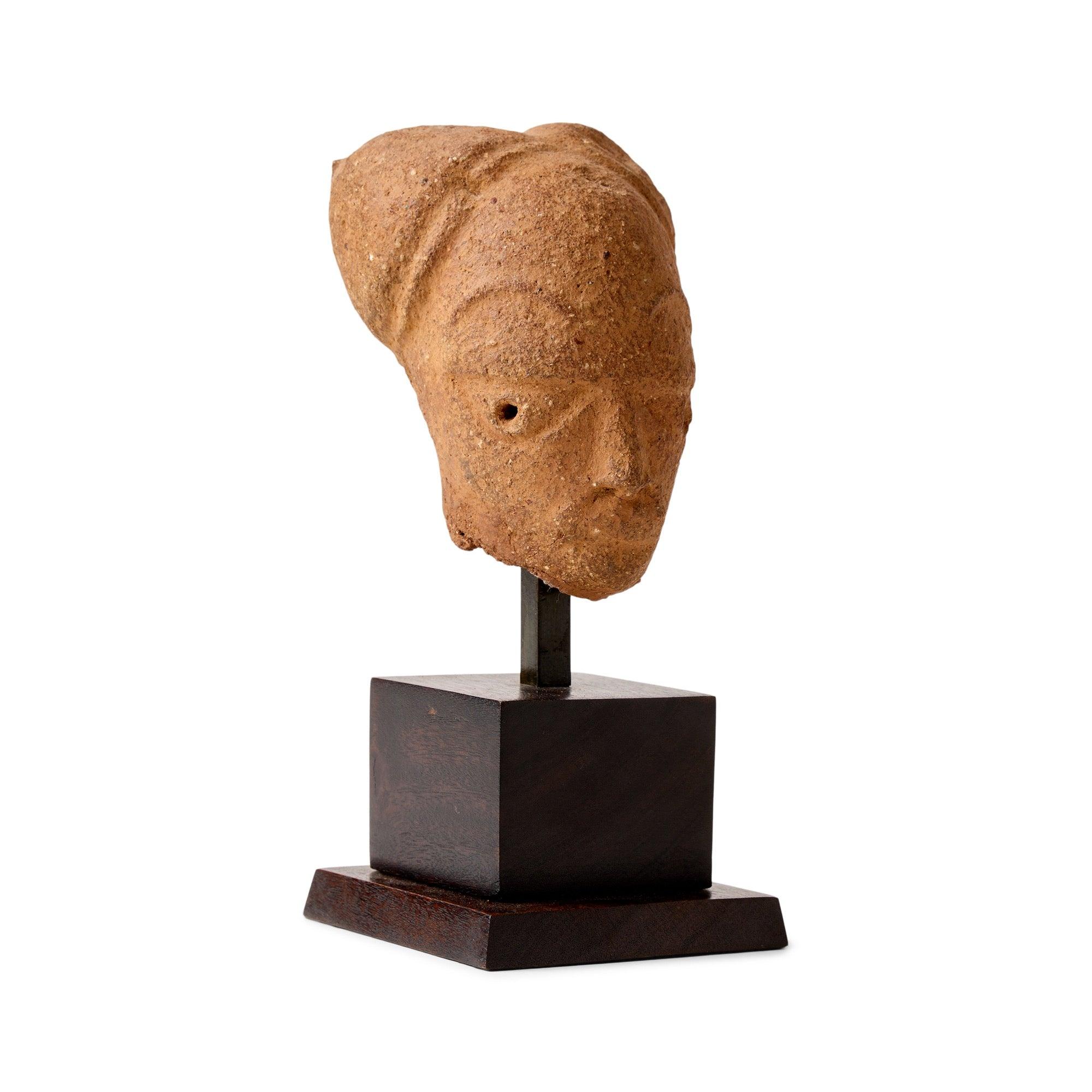 Resti di testa in terracotta su base di legno affusolata